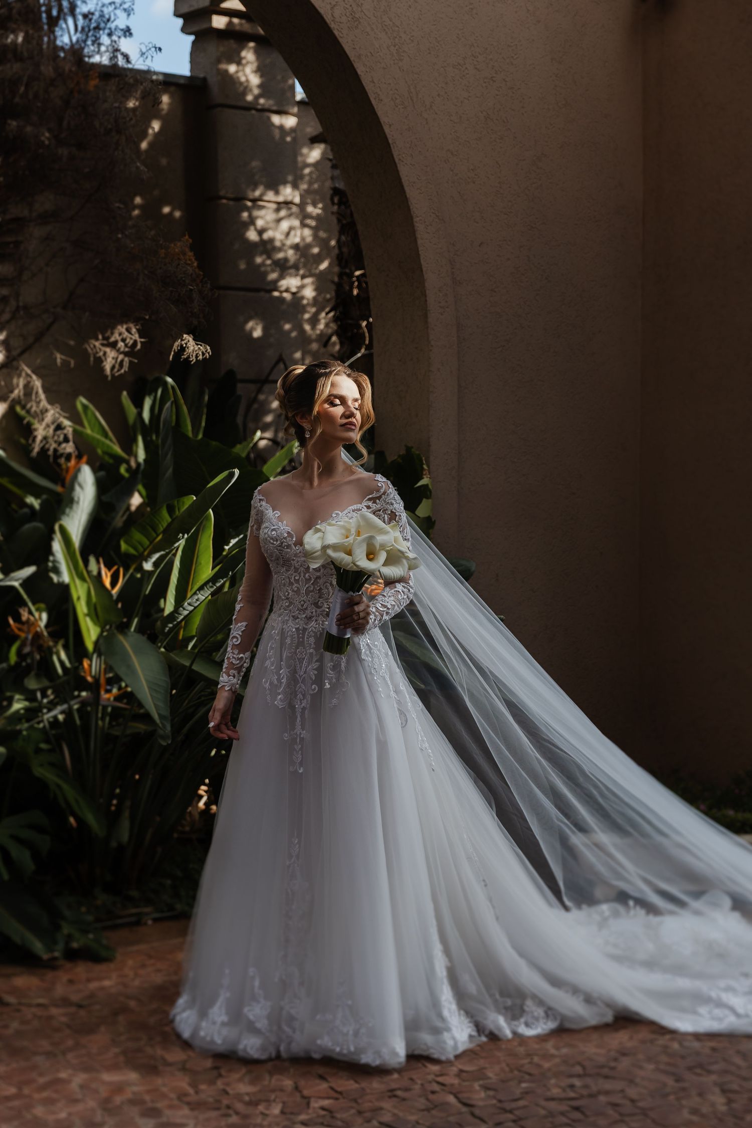 White lace wedding dress with flowing train captured in a series of romantic garden photos.