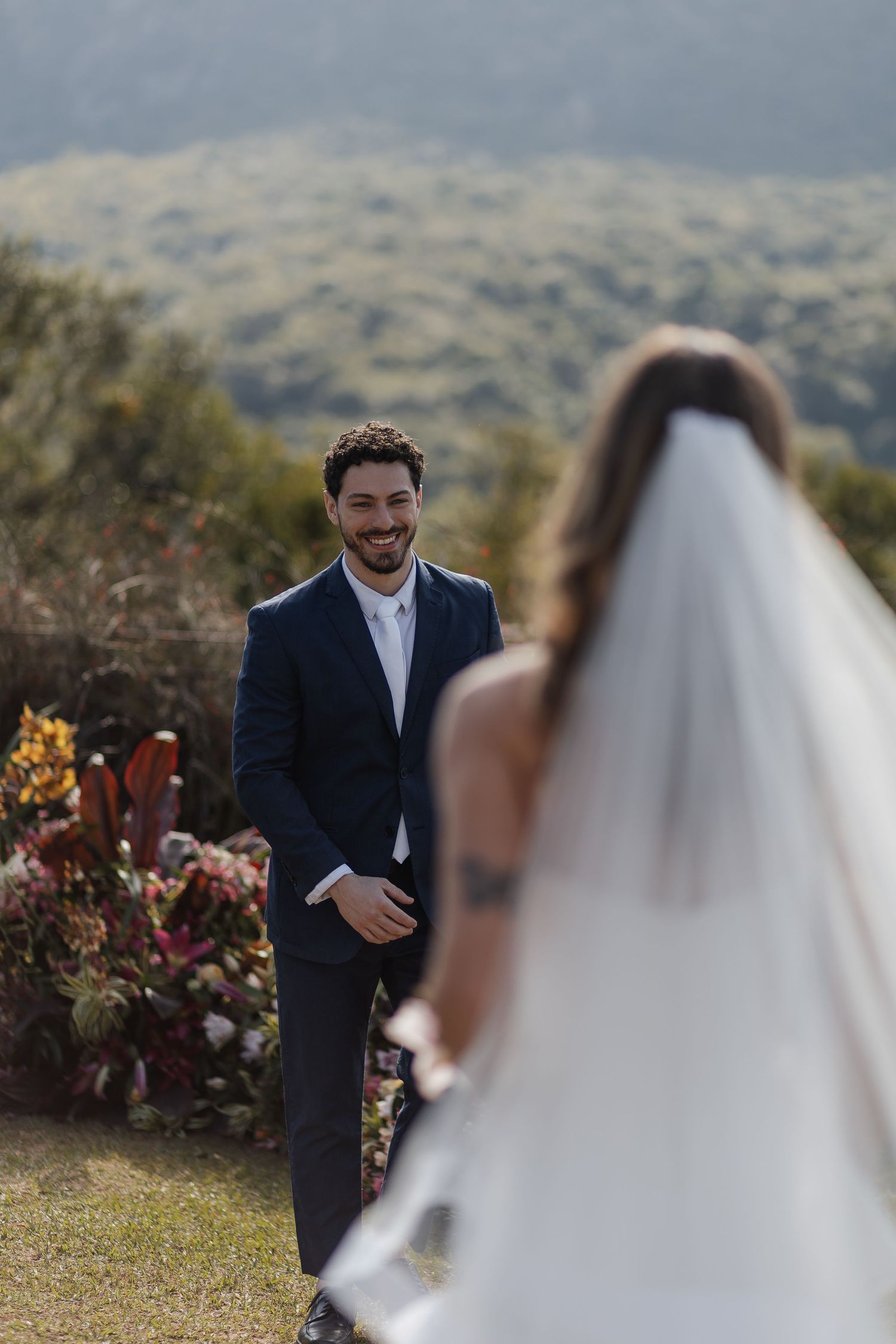 A candid first look moment captured at an outdoor wedding ceremony with distant mountains in the background.