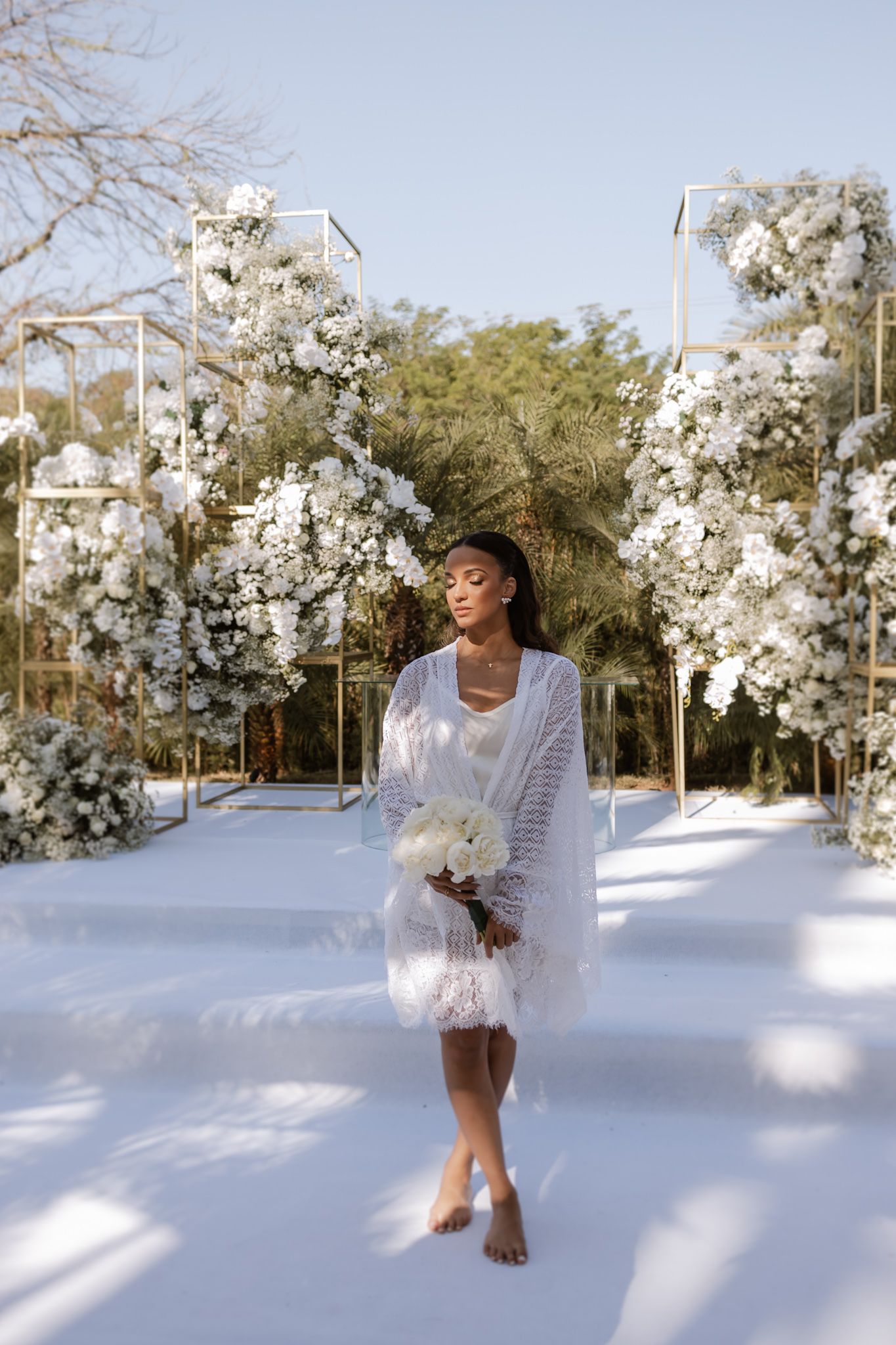 Elegant bridal look against stunning white floral arrangements in an outdoor wedding setting.LIAC