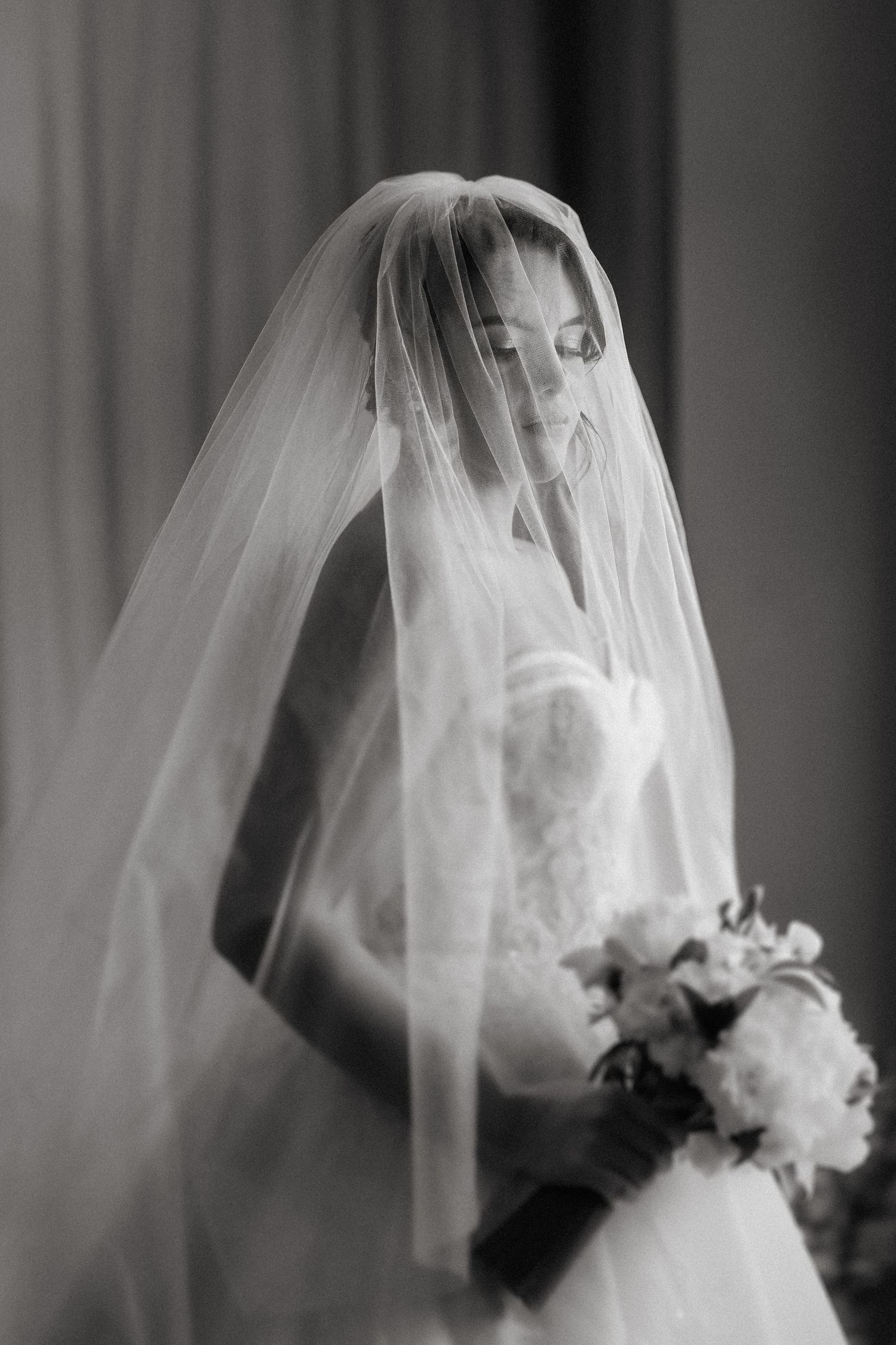 A dreamy black and white bridal portrait series showing a bride in a flowing veil holding a white bouquet.