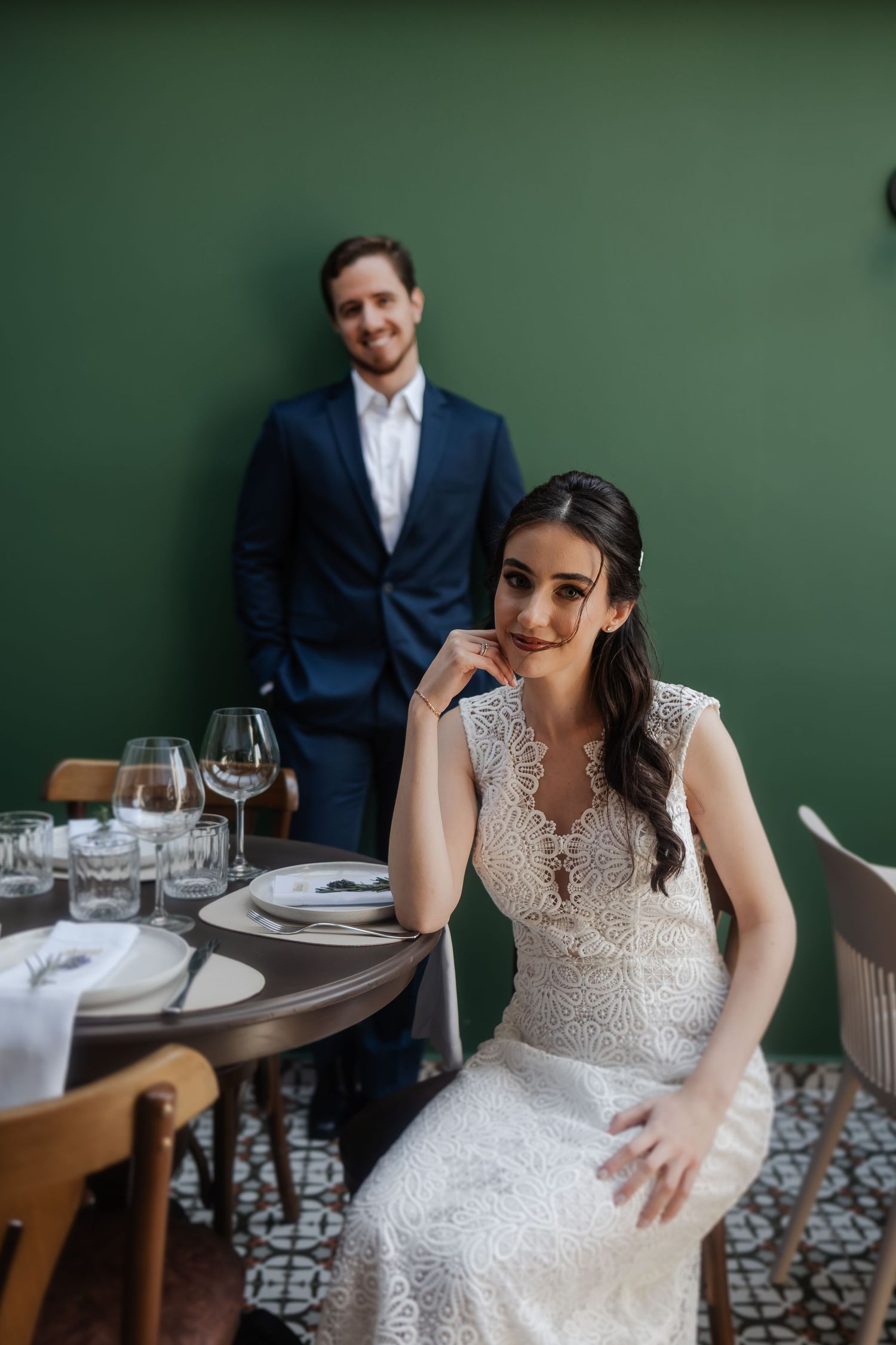 A series of wedding photos showing a bride in a lace dress seated at an elegant restaurant table with green walls.