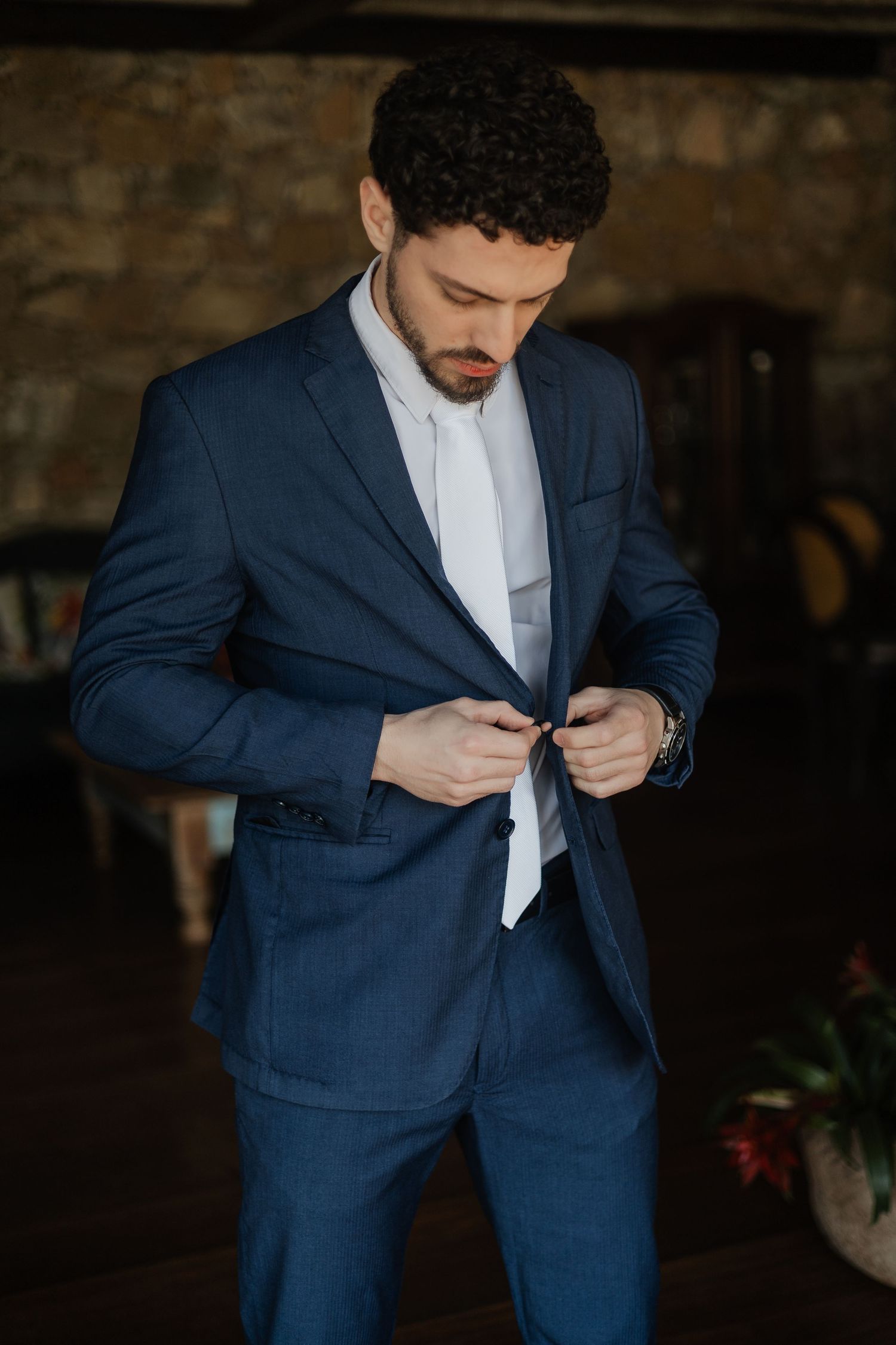 A sequence of images showing someone buttoning up a navy blue suit jacket with a white dress shirt.