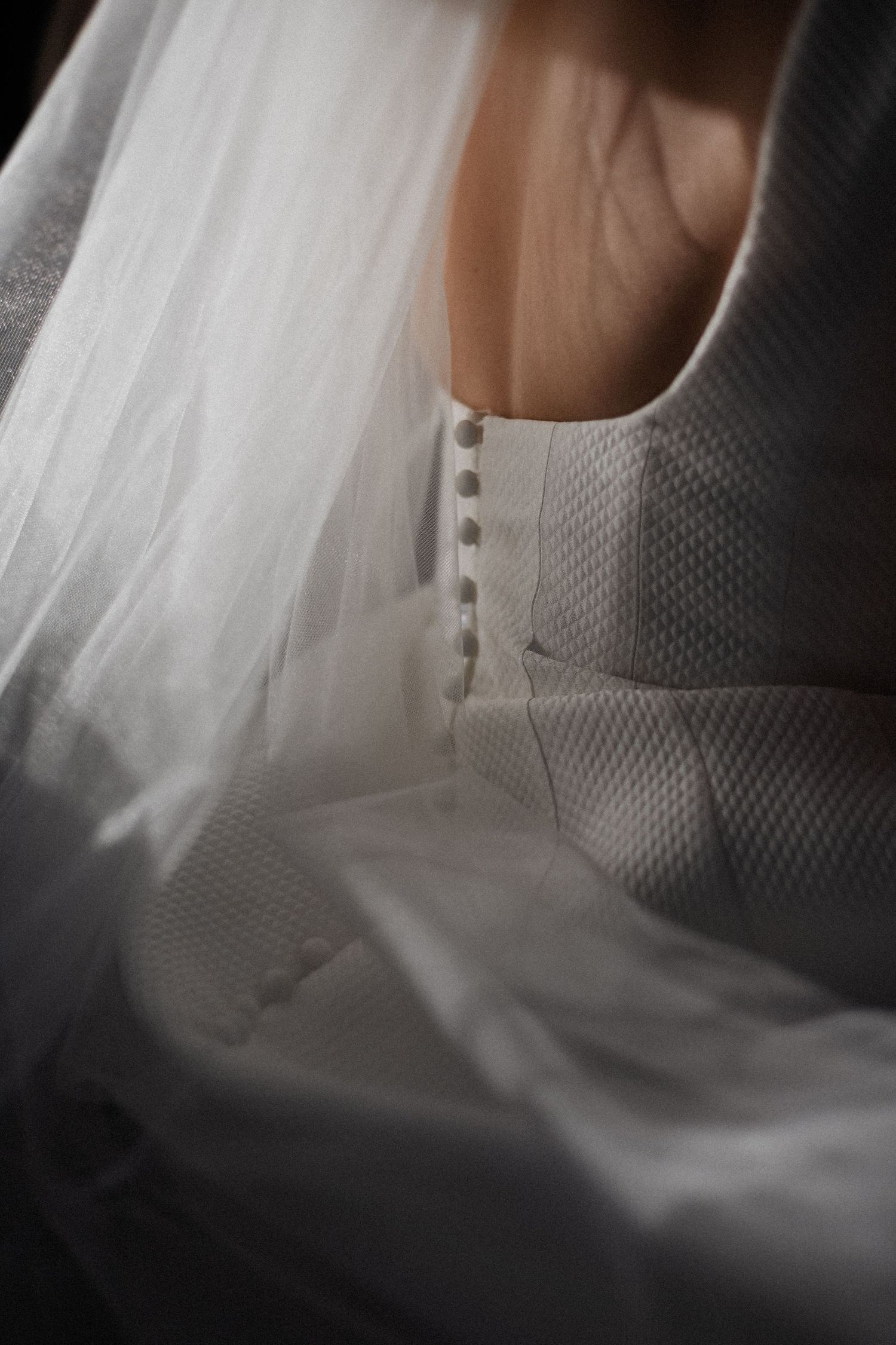 Close-up view of delicate white bridal veil fabric with soft texture and ethereal lighting.