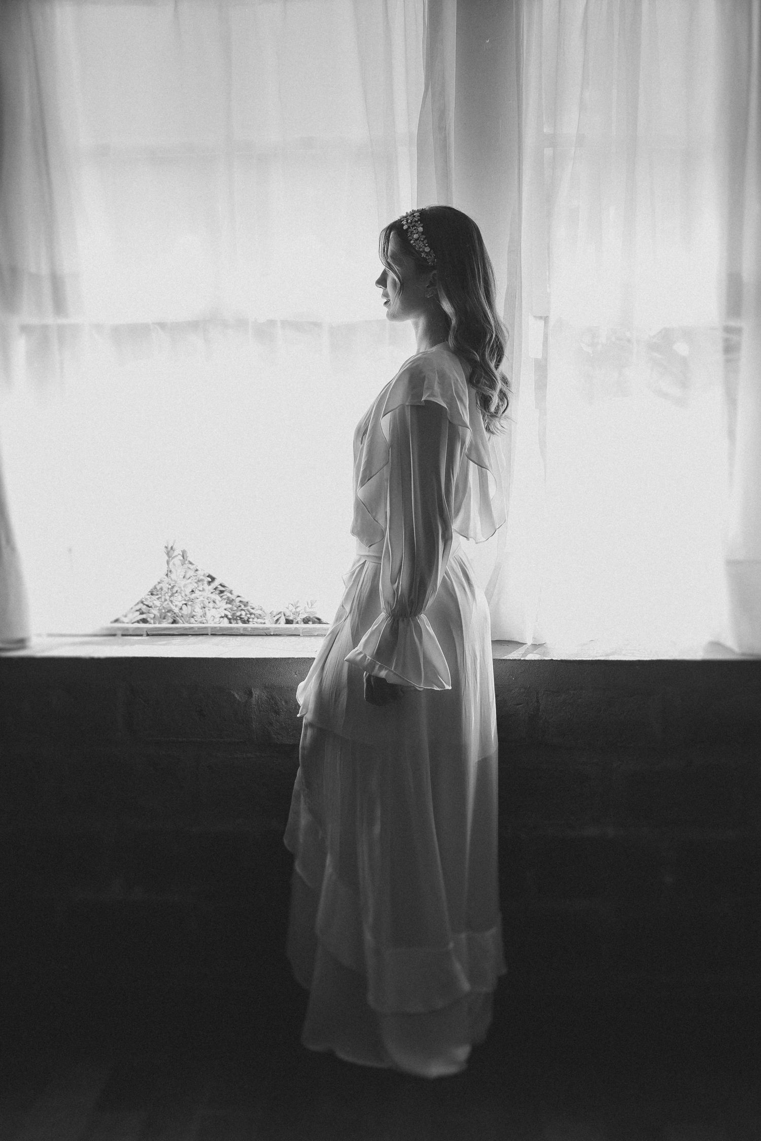 A series of five dramatic black and white silhouettes showing a figure in white standing by windows with curtains.