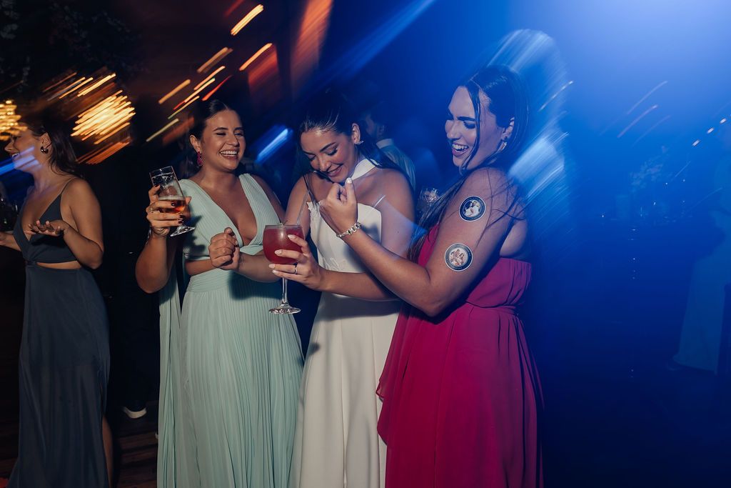 Group of women in formal dresses smiling and having drinks at a festive nighttime celebration.