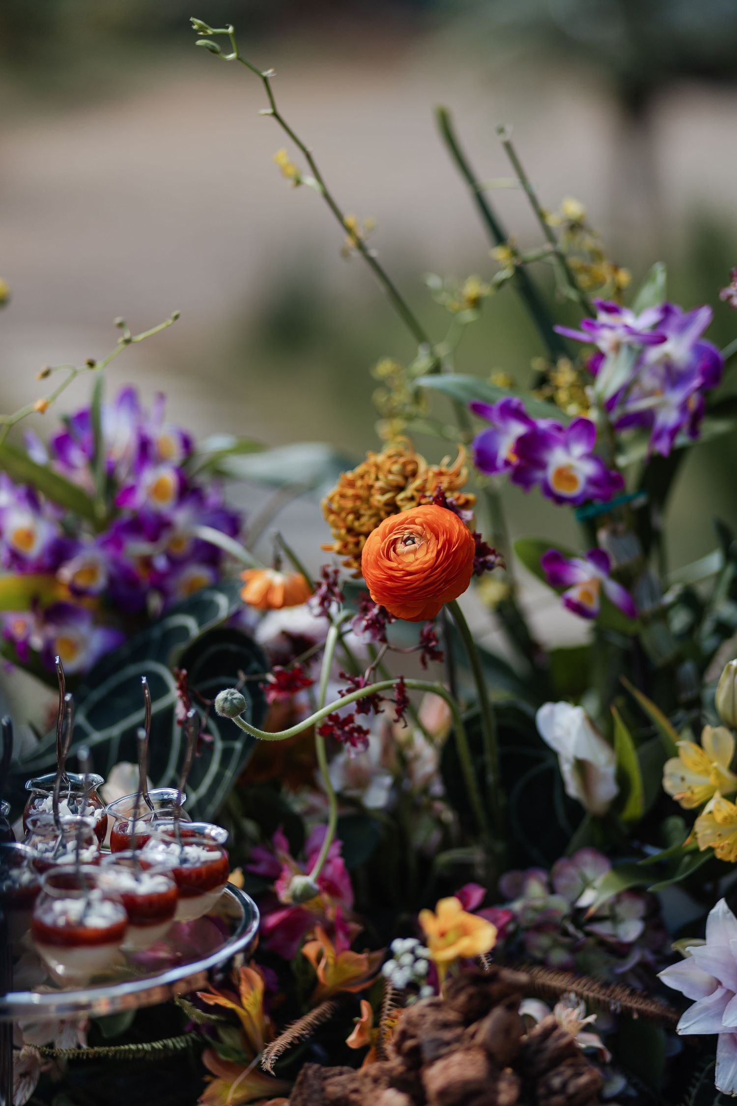 Elegant table setting with colorful flowers, ranunculus, and delicate glassware arranged for a romantic garden party.