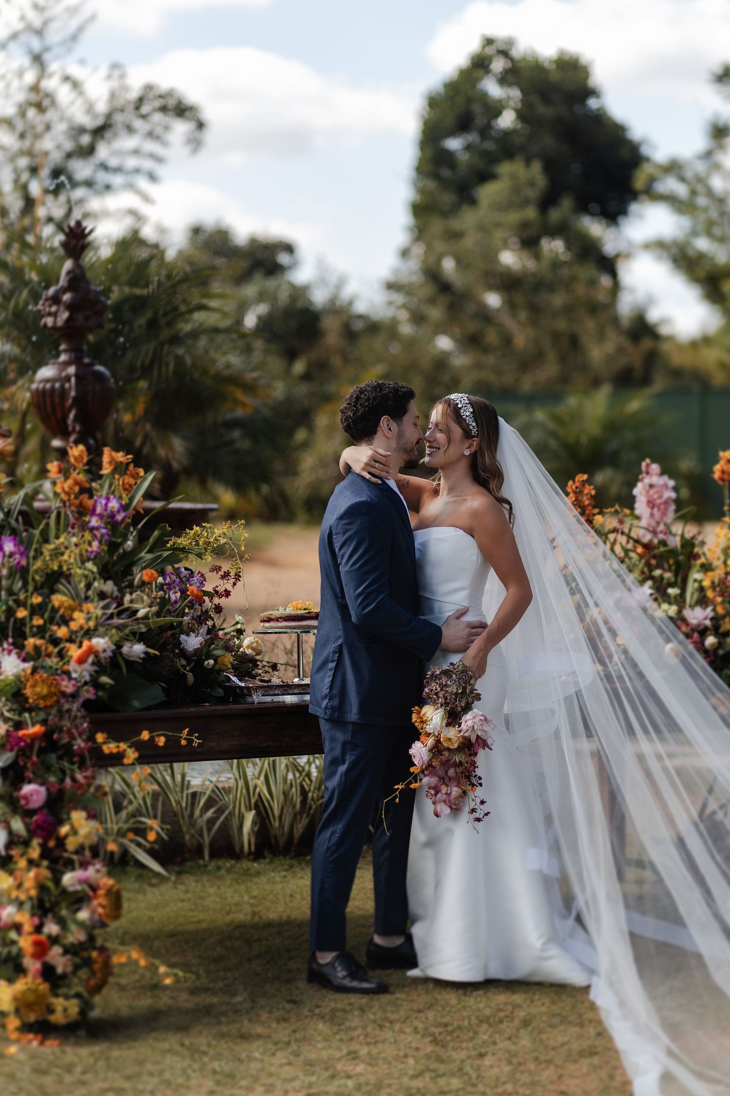 A romantic outdoor wedding ceremony with flowing veil and vibrant floral arrangements in a garden setting.