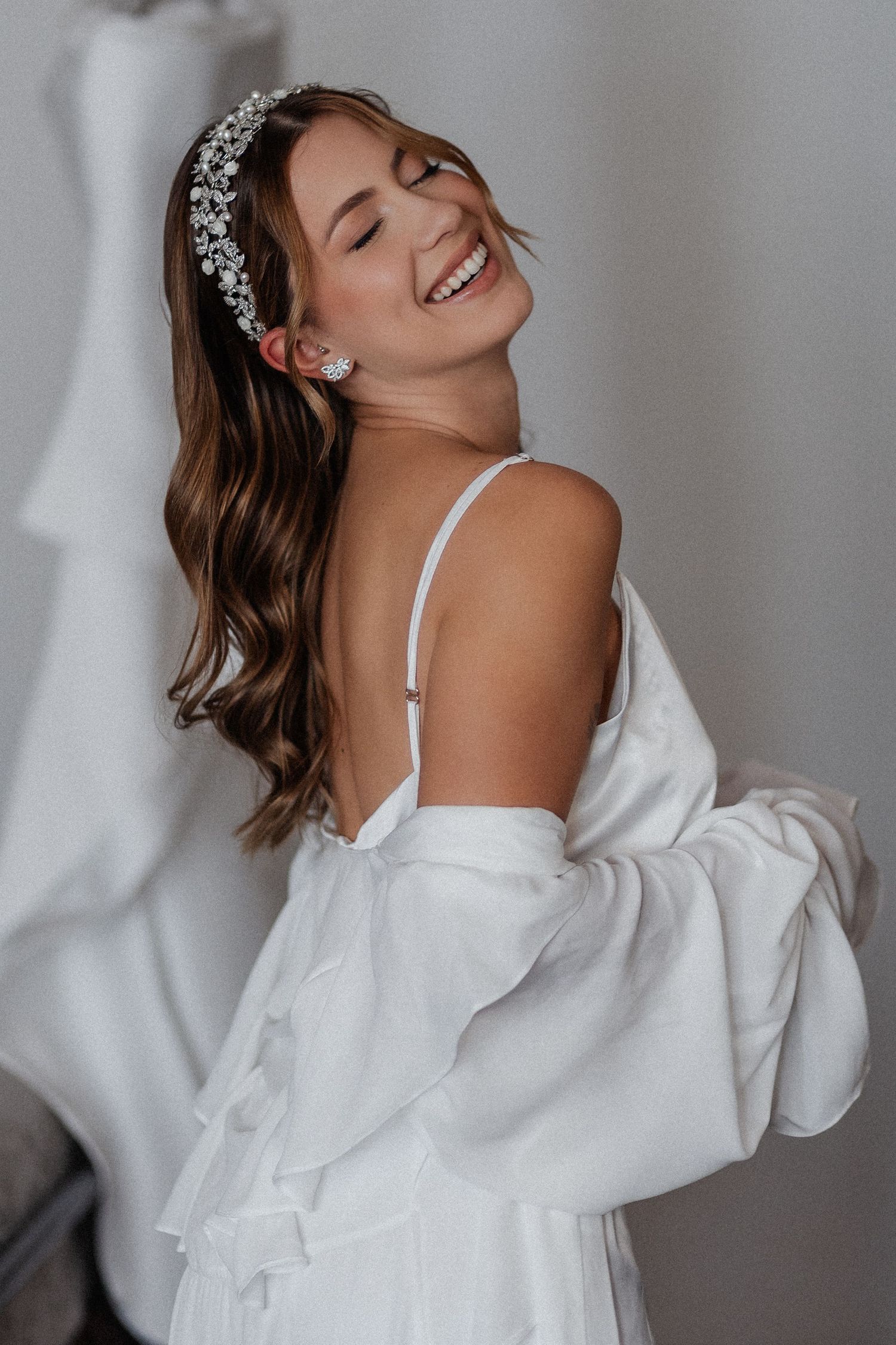 A joyful bride in an off-shoulder white gown and crystal headpiece poses naturally in a stylized photo sequence.