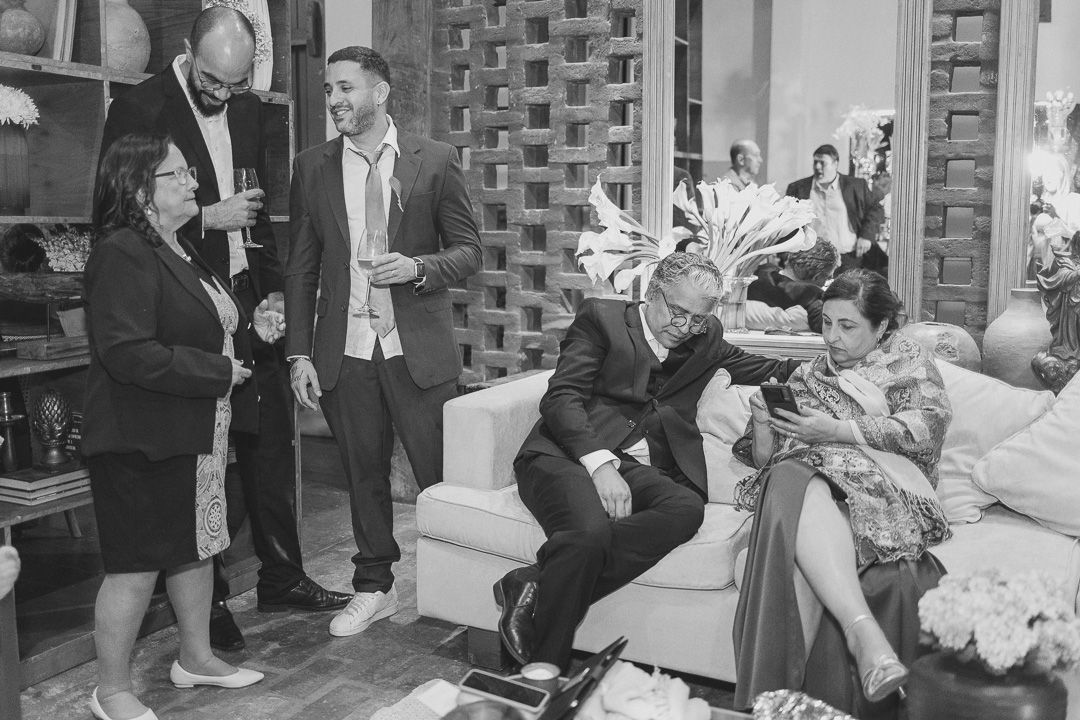 A group of people socializing at a party in a living room with mid-century modern decor and furnishings.