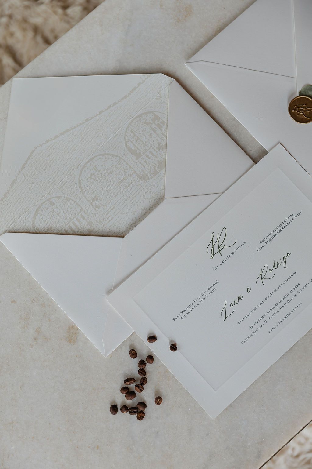Cerimônia de casamento ao ar livre nElegant white wedding invitations with envelopes and scattered coffee beans on a light textured surface.