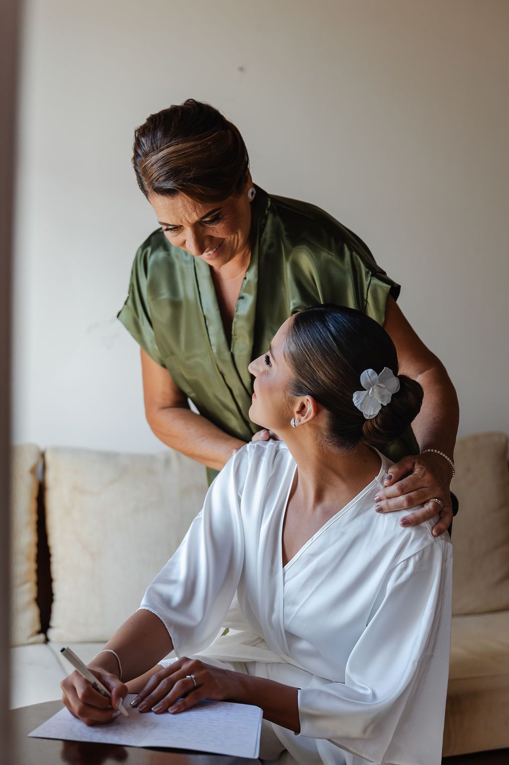 Cerimônia de casamento ao ar livre A joyful moment shared between two women in white and green outfits while looking over paperwork at home.