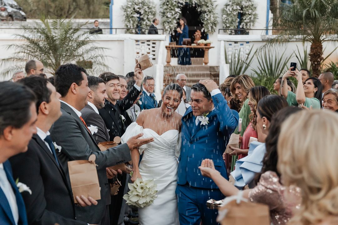 Wedding celebration at outdoor venue with guests cheering during garden ceremony exit.