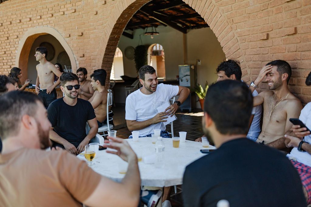 Cerimônia de casamento ao ar livre group of people gather around a table for a casual outdoor meal at a restaurant with arched architecture.