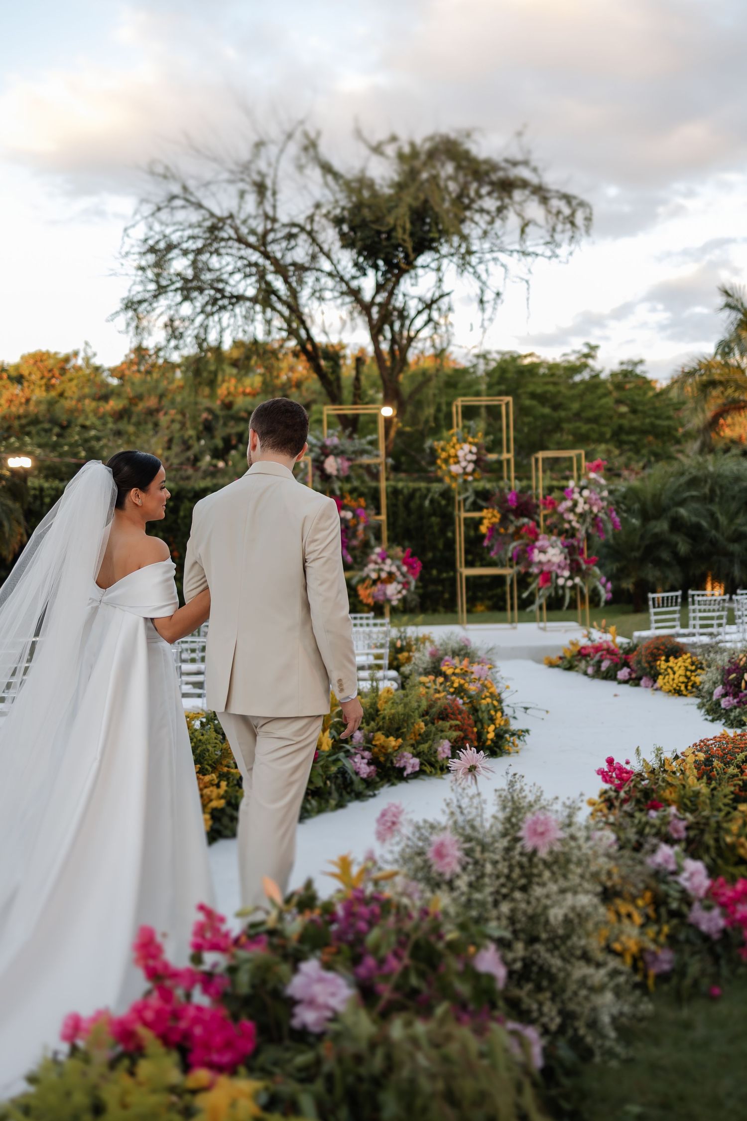 Newlyweds share intimate moments in a garden setting surrounded by vibrant flowers and natural decor.