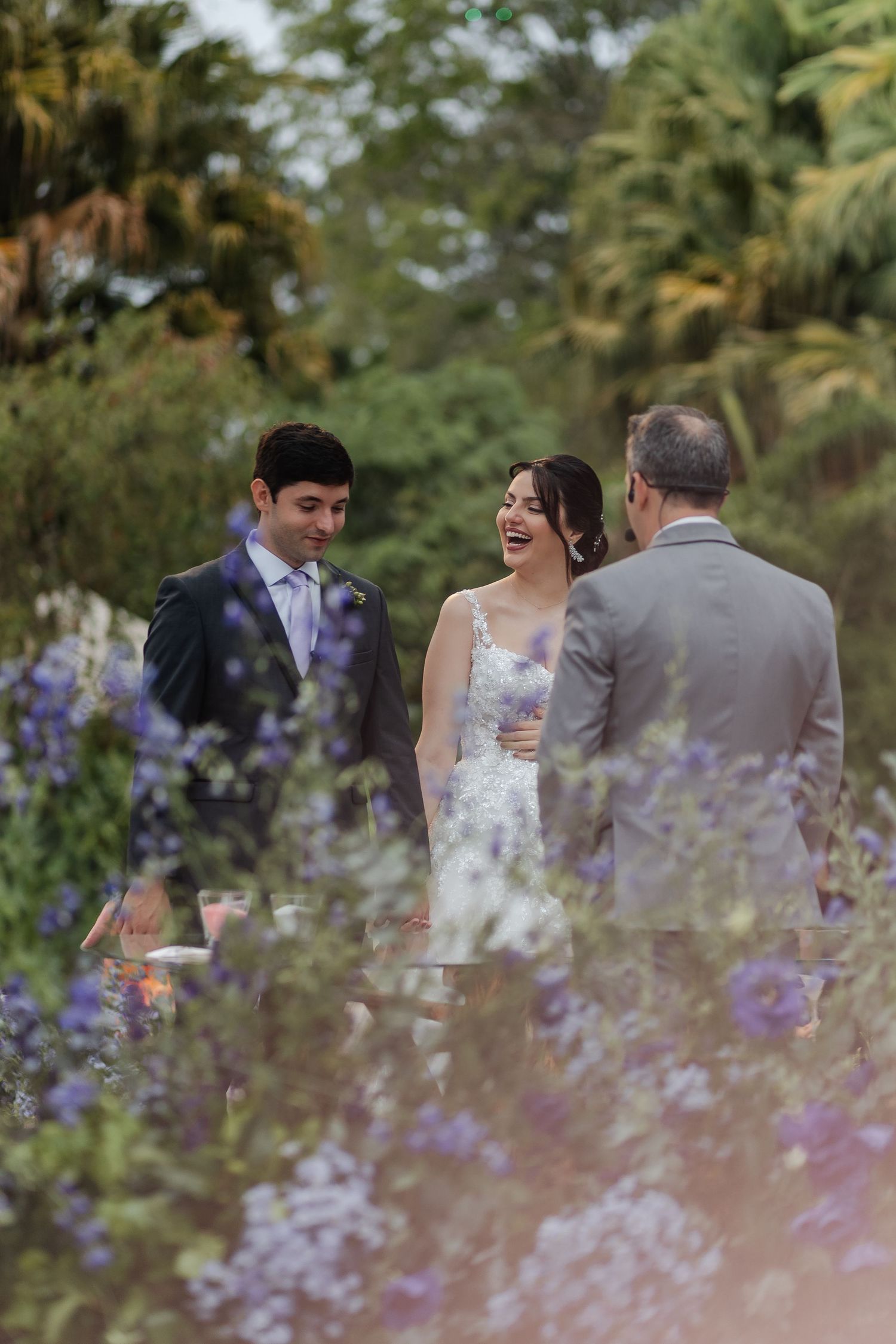 Wedding couple shares an intimate moment in a garden with purple wildflowers in the foreground.