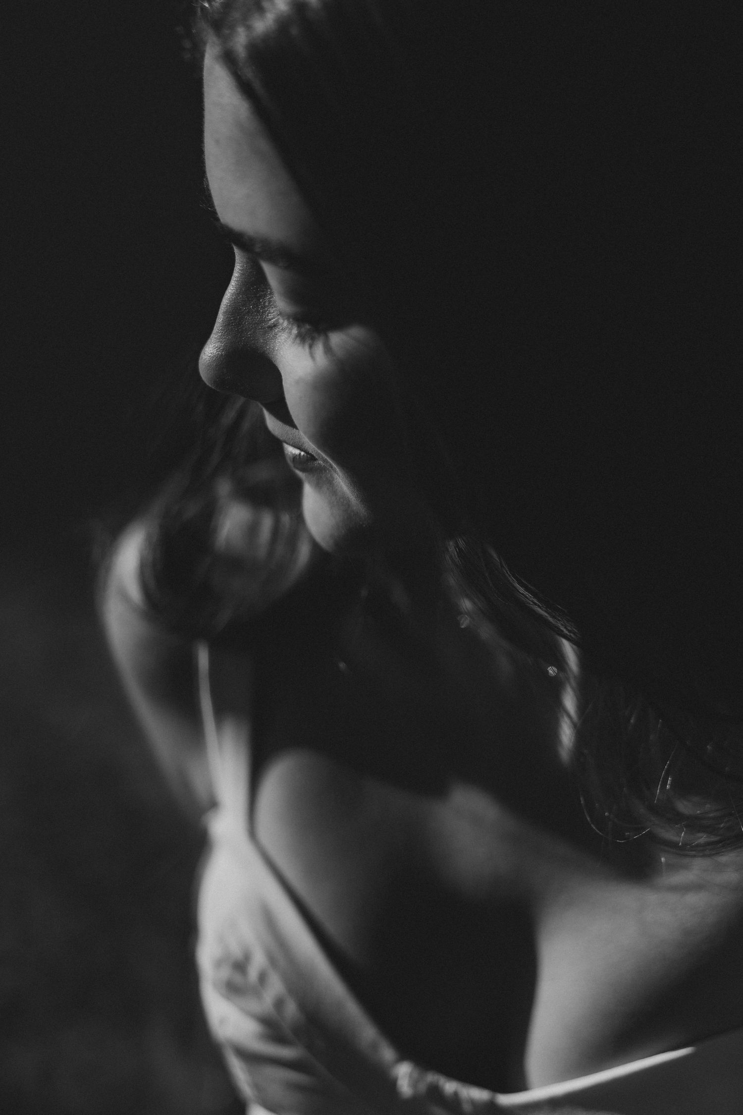A dramatic black and white side profile portrait highlighting shadows and light against dark moodiness.