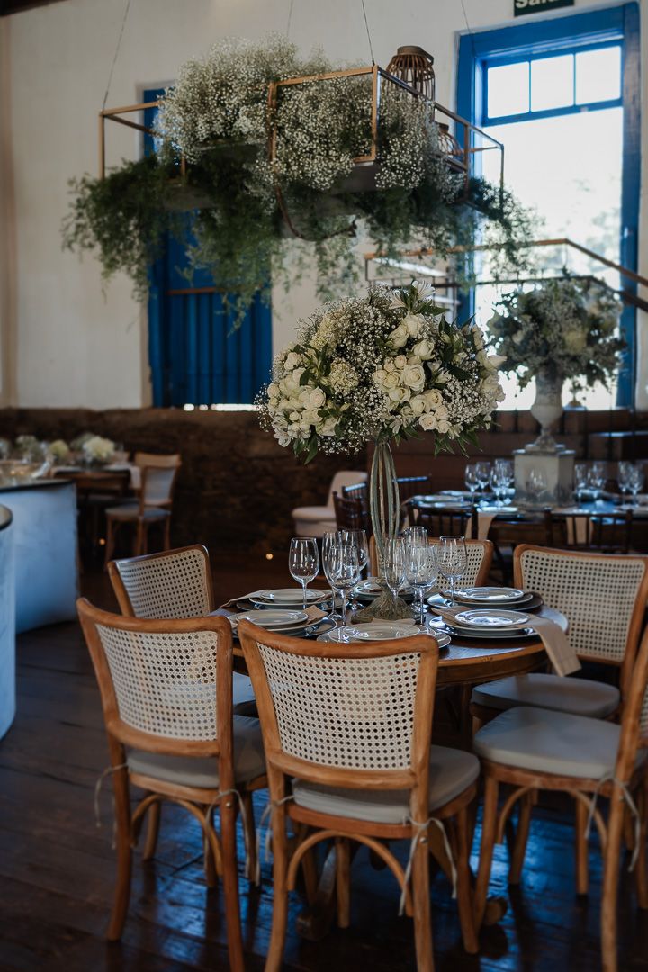 Foto do casal na FElegant wedding table setting with cane back chairs and dramatic floral centerpiece in white and blue restaurant interior.