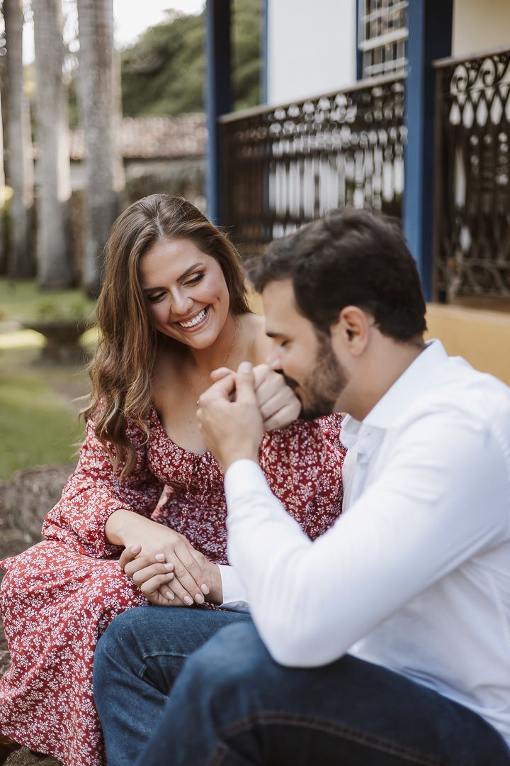Romantic couple sharing an intimate moment outdoors with a woman in a red floral dress and man in white shirt.