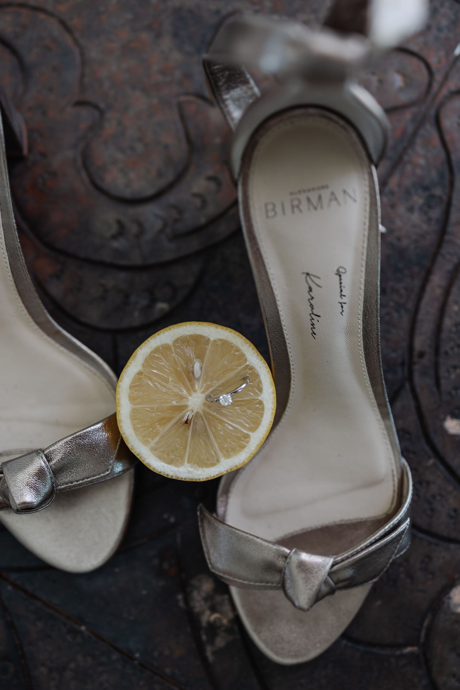 Artistic sequence showing a silver high heel shoe with a lemon slice placed on top against a dark textured background.