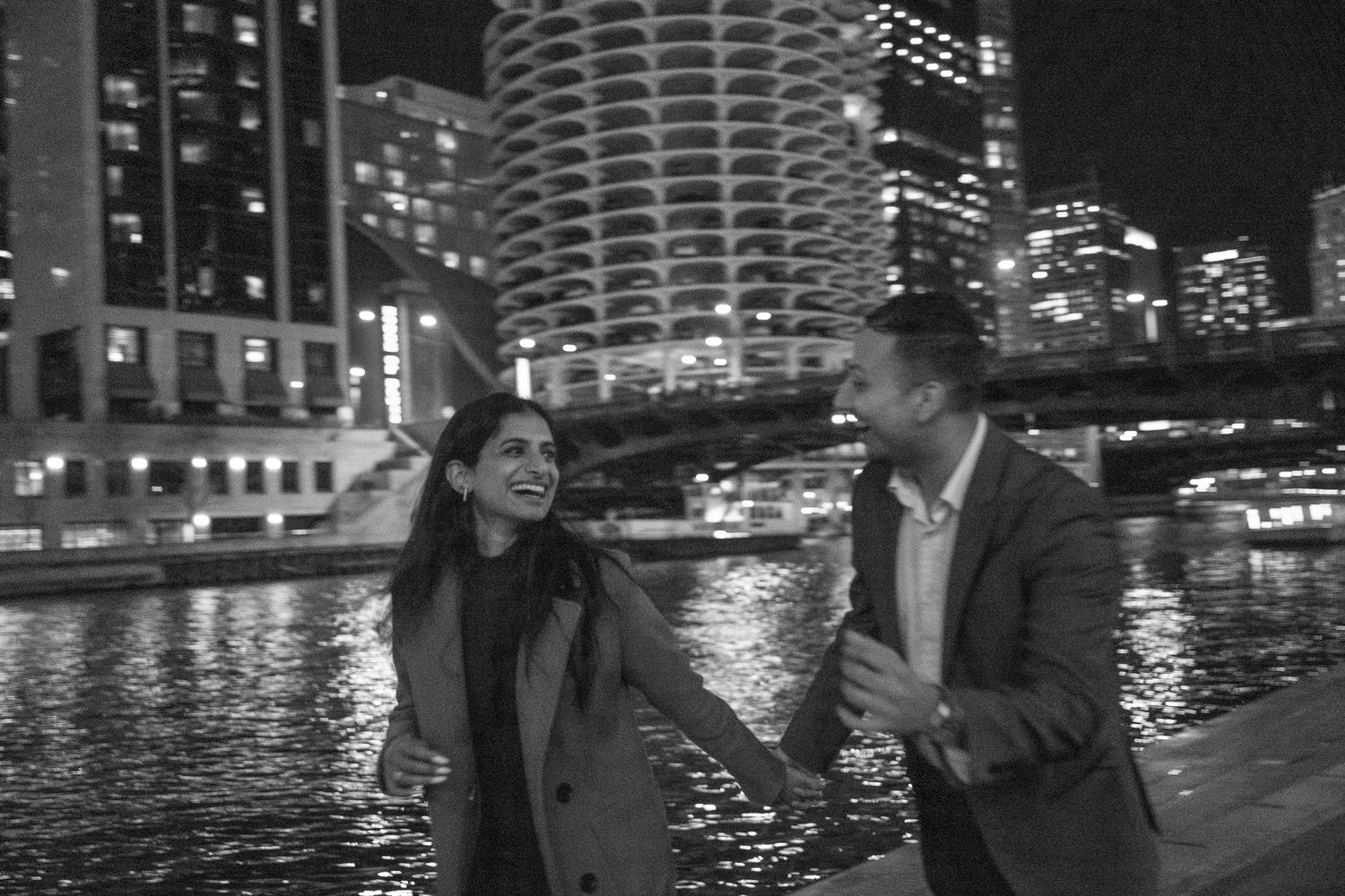 Happy couple enjoying nighttime stroll along illuminated Chicago River.