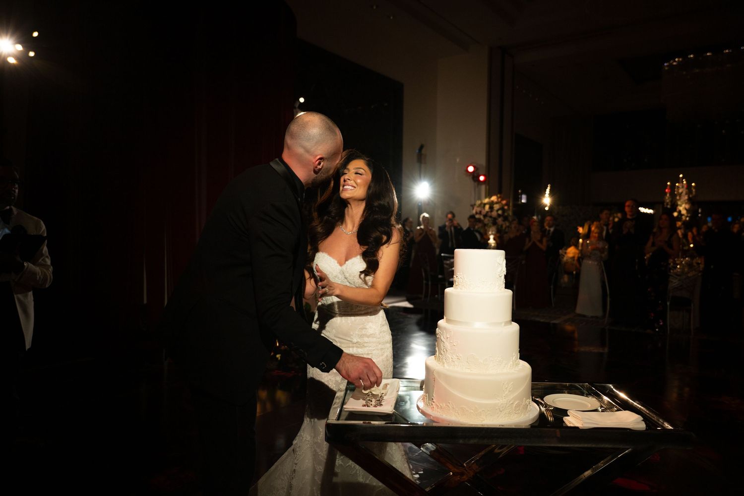 A series of photos showing a wedding cake cutting ceremony in a dimly lit reception venue at night.