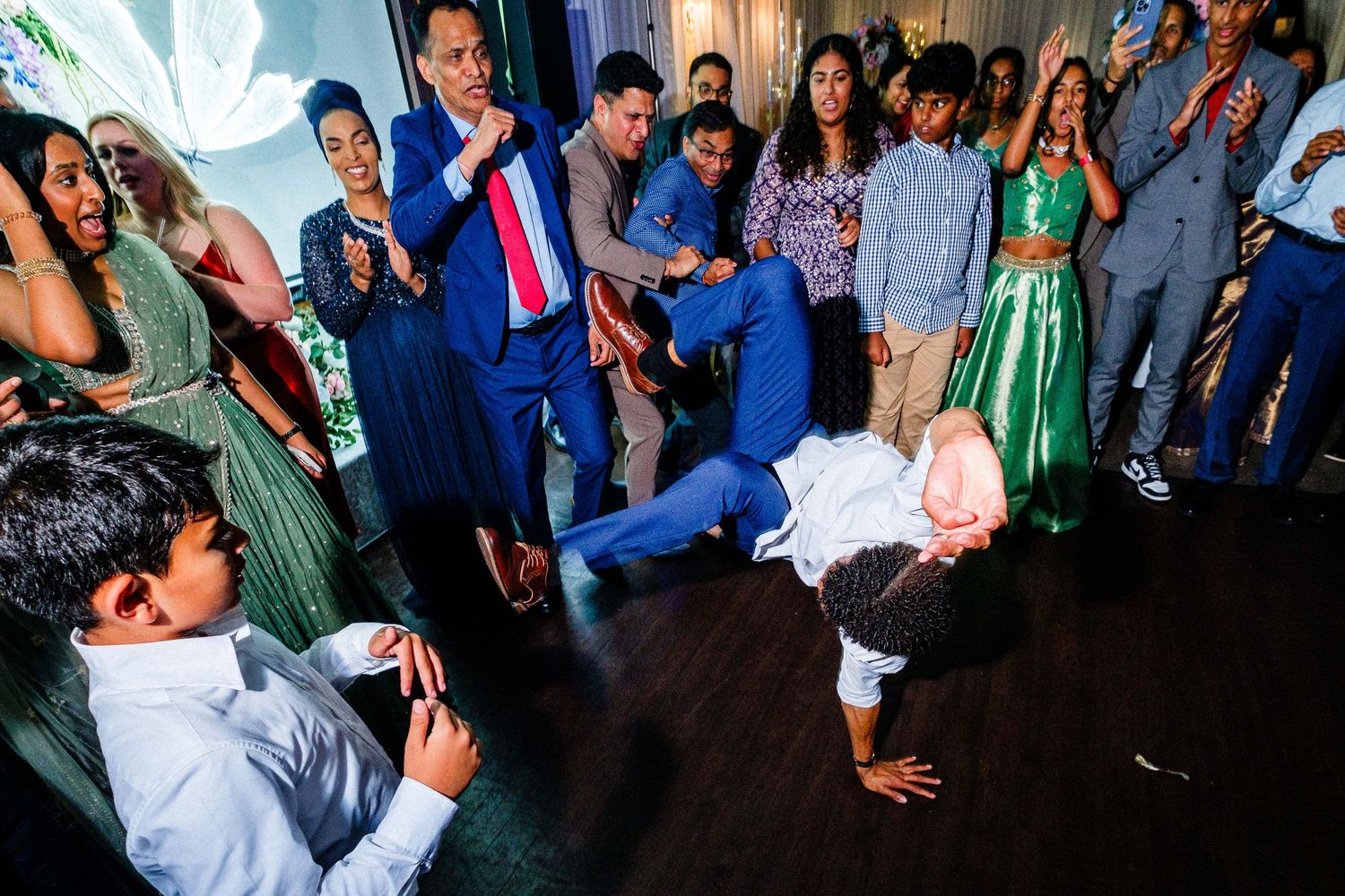 Party guests dancing and celebrating on a crowded dance floor with blue lighting.