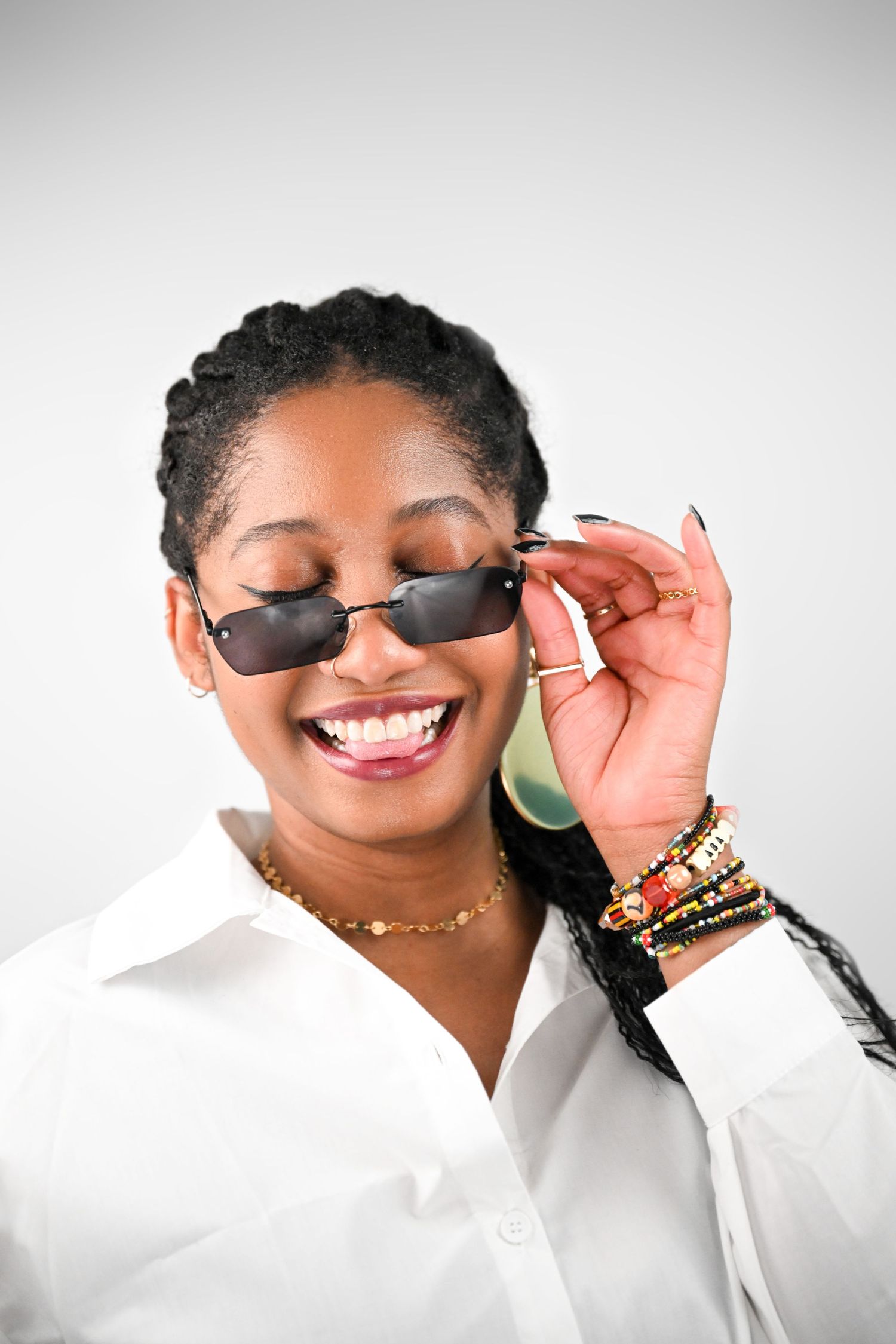 Stylish portrait featuring trendy small sunglasses and white button-up shirt against light background.