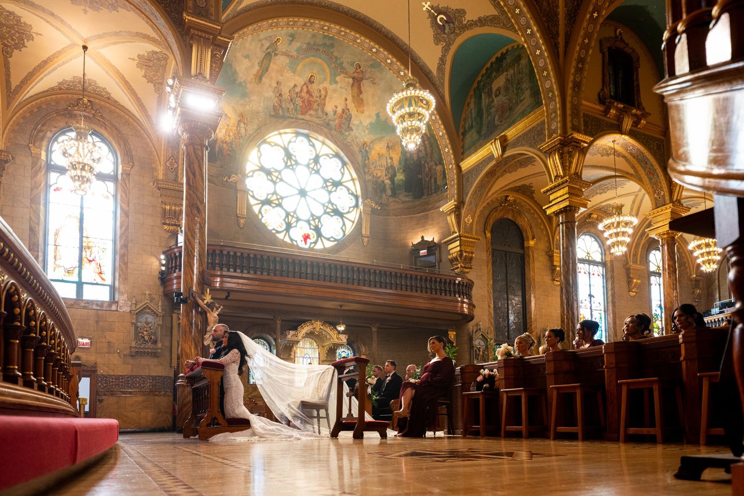 Ornate interior of a historic church with vaulted ceilings, stained glass windows, and detailed religious murals.