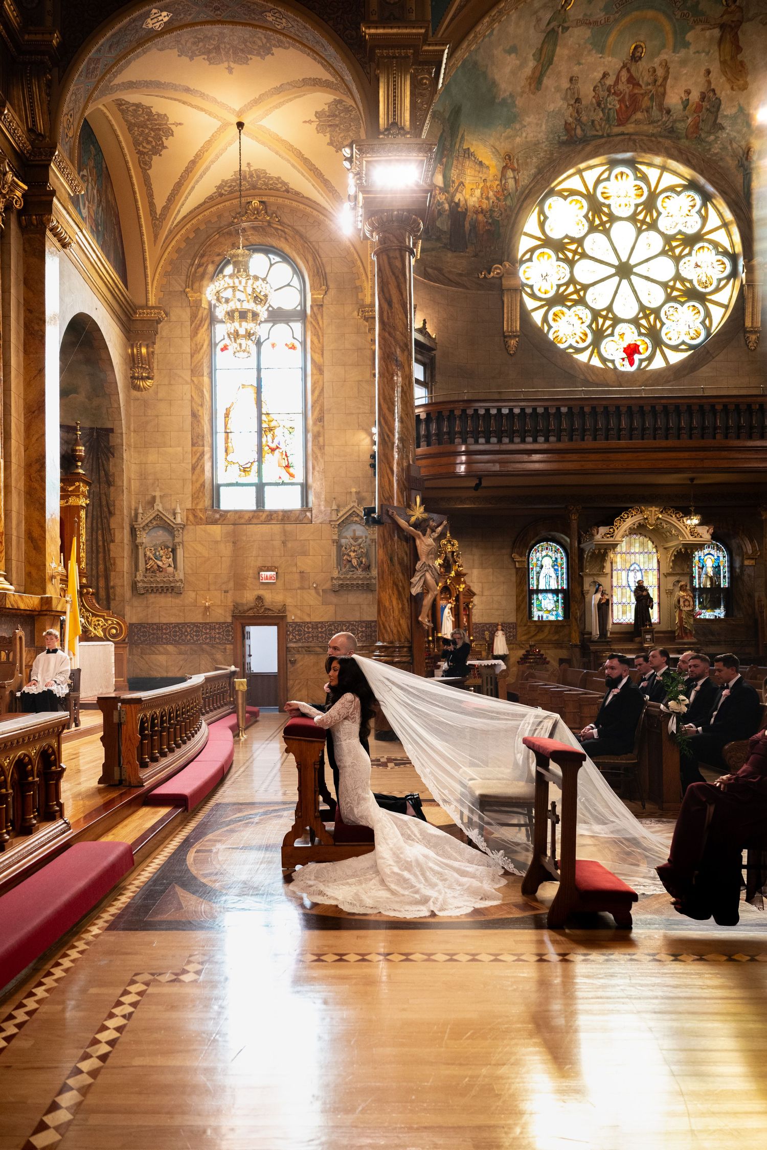 A stunning cathedral interior with vaulted ceilings, stained glass windows and a dramatic wedding ceremony in progress.