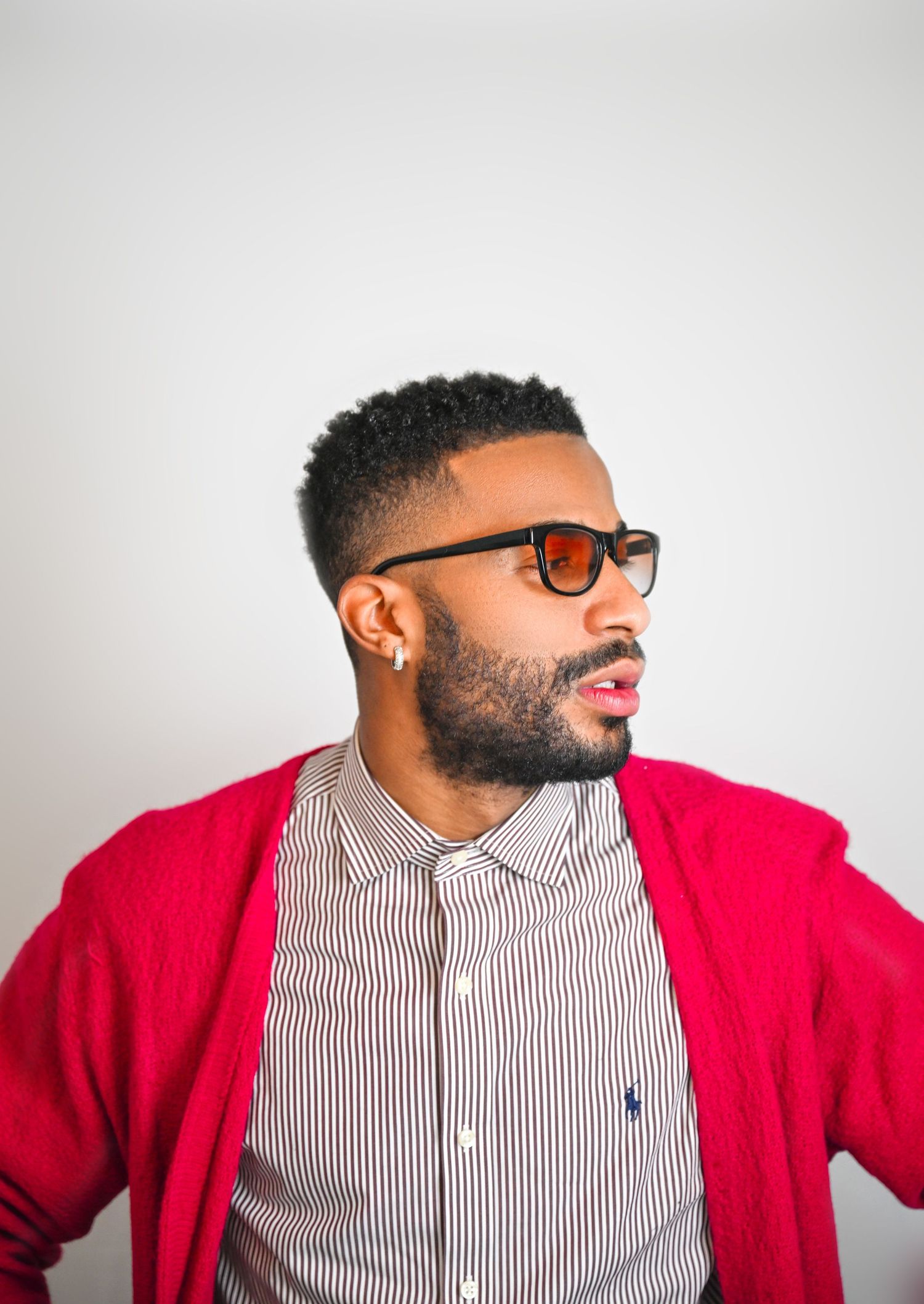 A person wearing glasses and a red cardigan with striped shirt poses against a white background in a sequence of shots.
