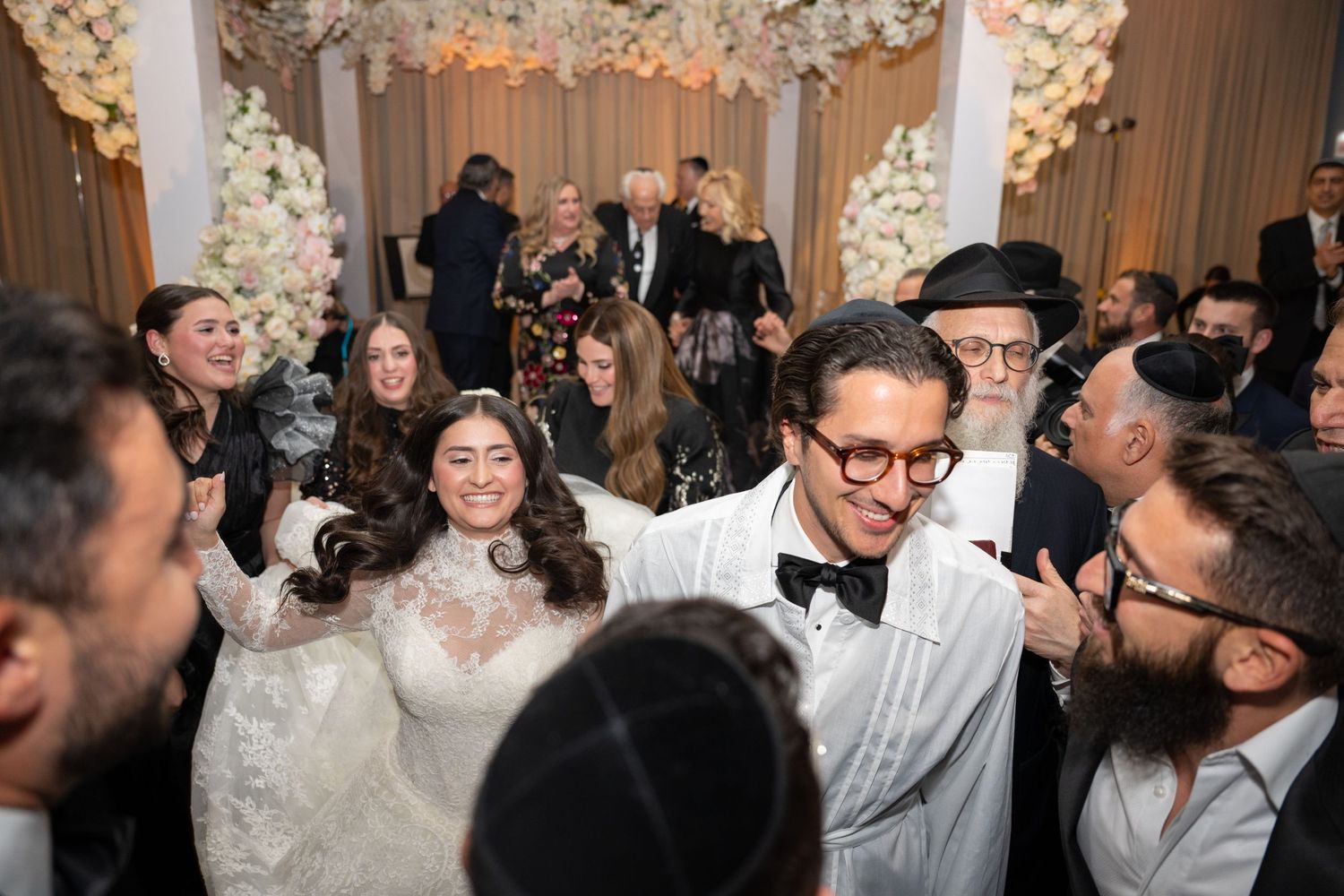A lively Jewish wedding celebration with guests dancing and celebrating in a traditional circle dance formation.