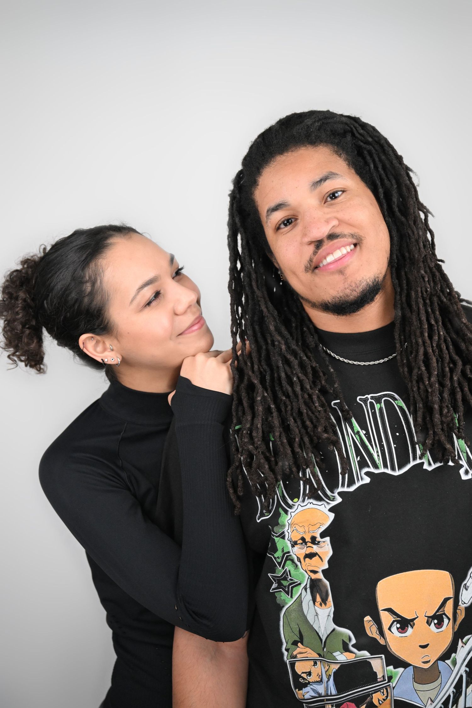 Two people sharing a playful moment while posing against white background.