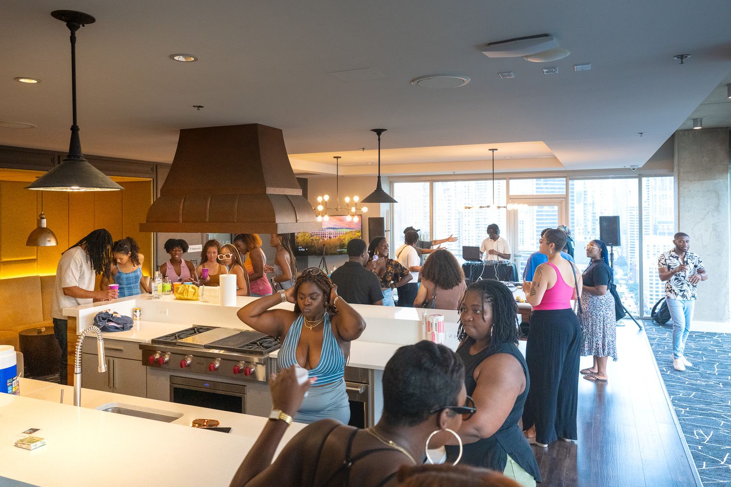 People gather in modern dining space with bar seating and pendant lighting.