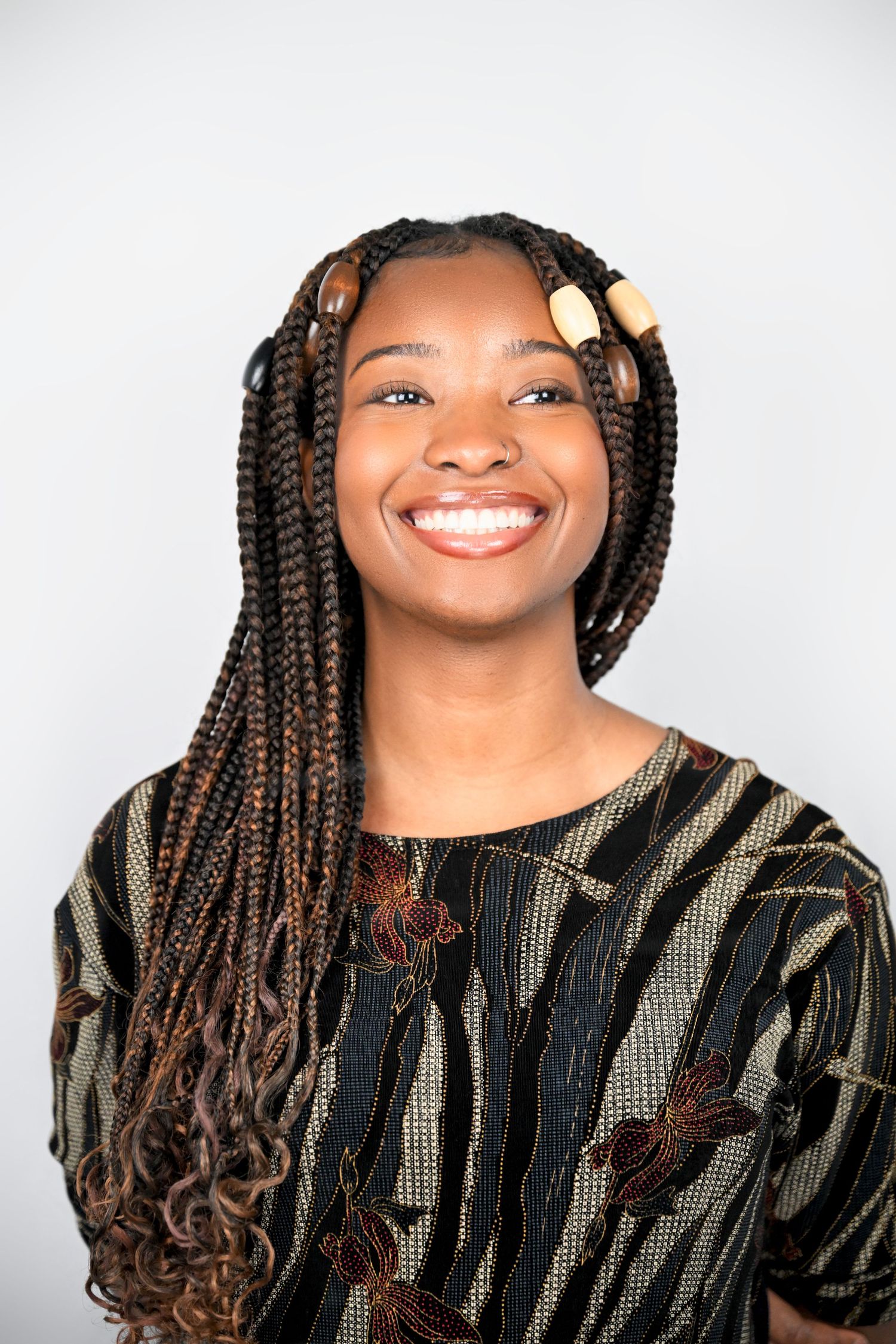 Close-up portrait showing radiant smile and detailed braided hairstyle with beaded accents.