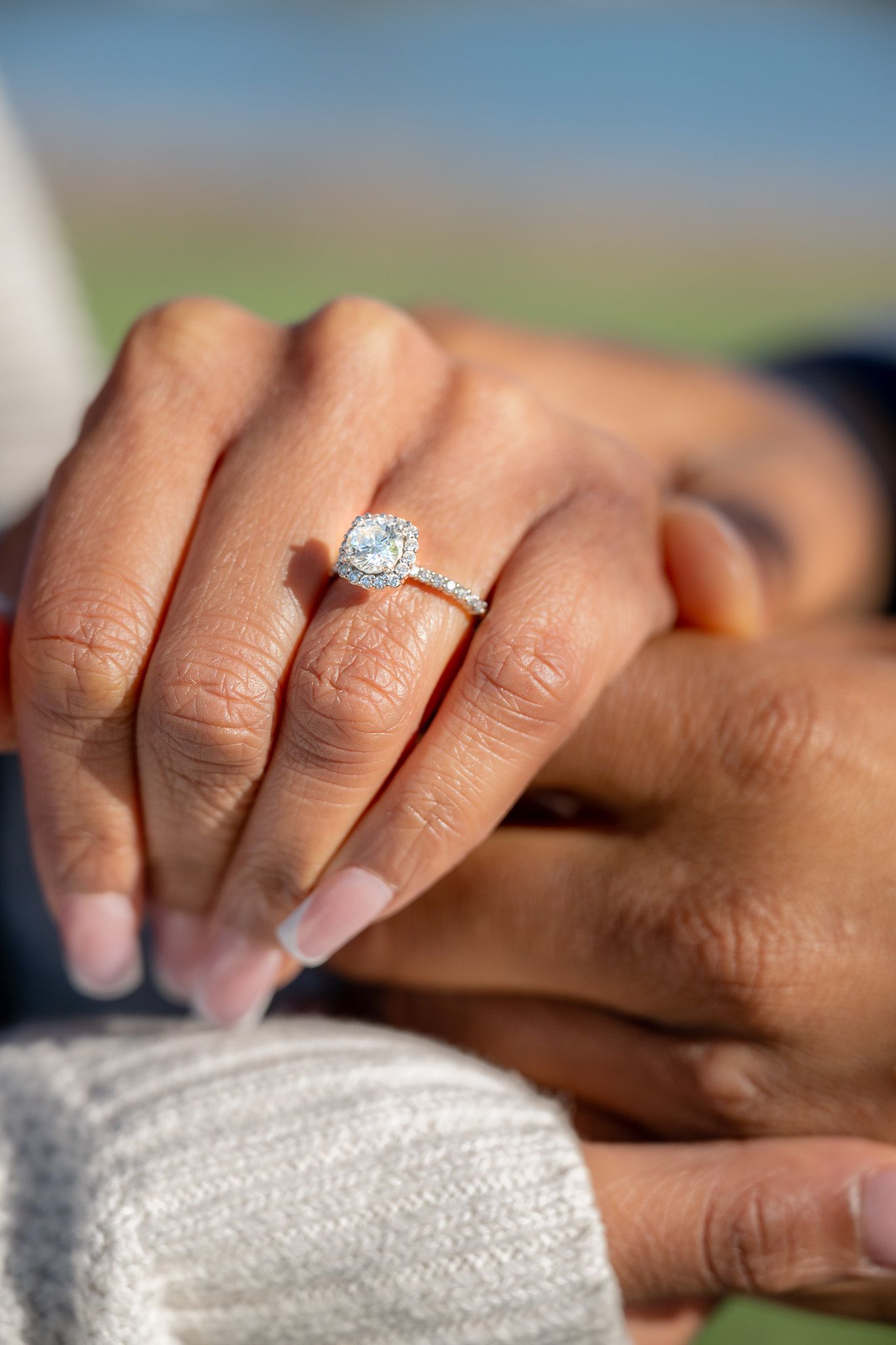 Close-up of a diamond engagement ring on a hand with natural lighting.
