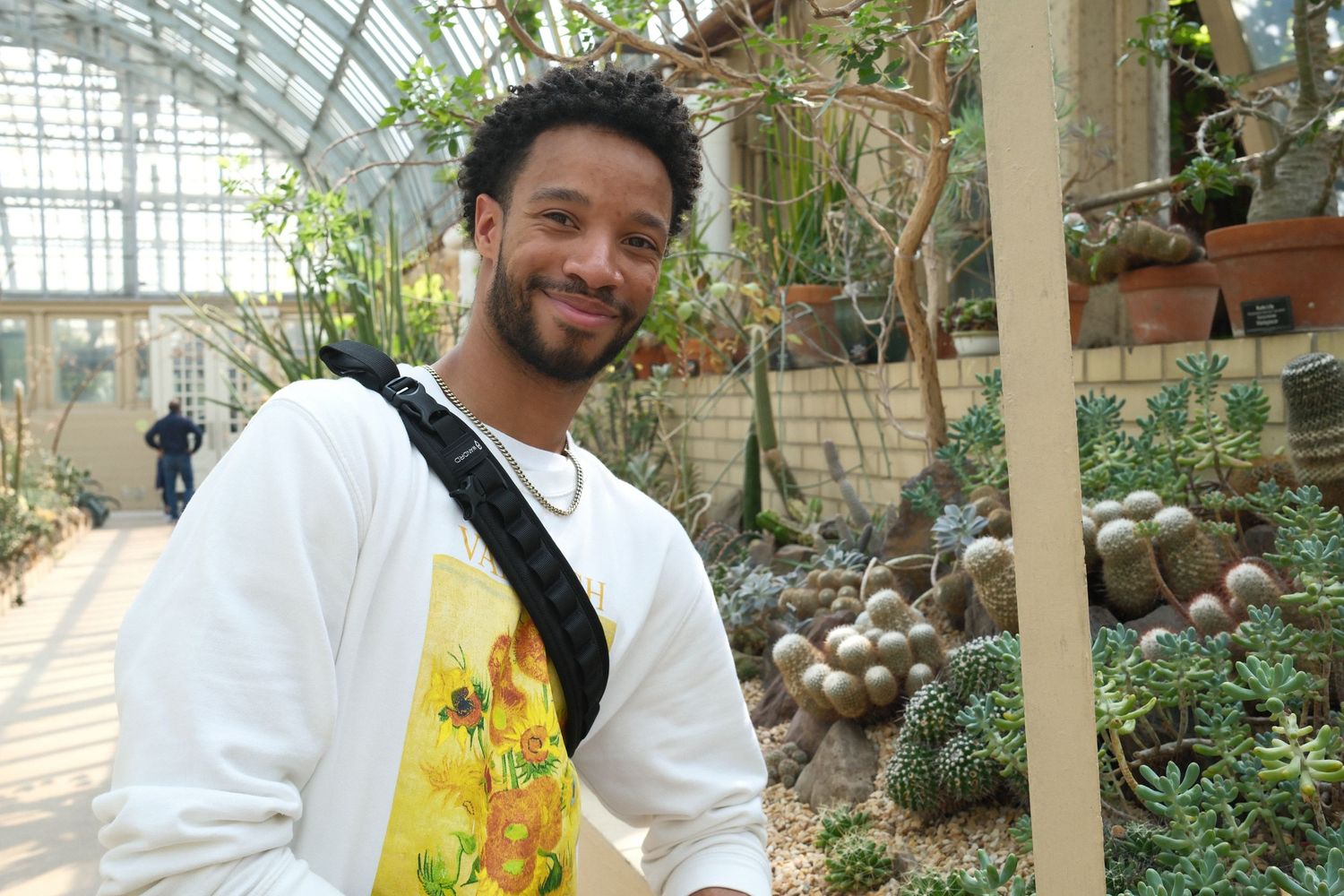 People in white lab coats working together in a bright greenhouse environment.