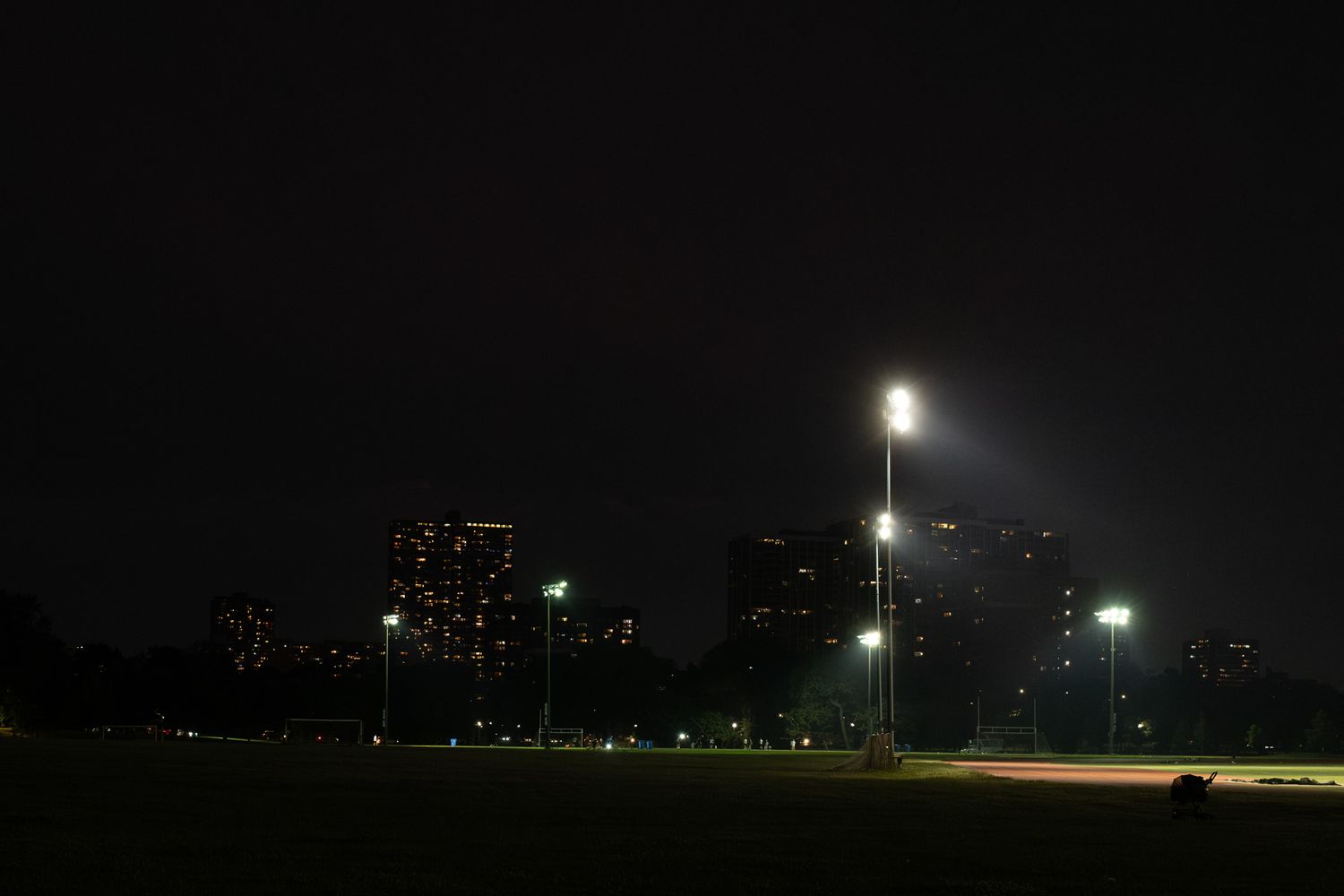 City skyline silhouetted at night with illuminated street lamps in the foreground.