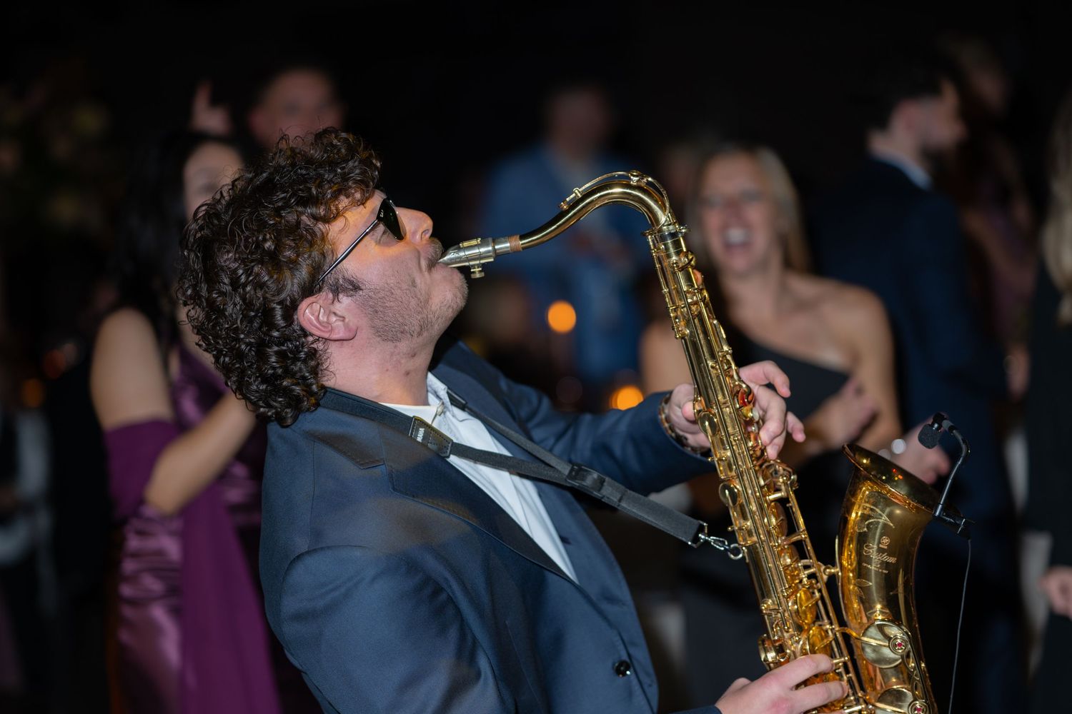 Saxophone player performs with passion during a live music event at a crowded venue.