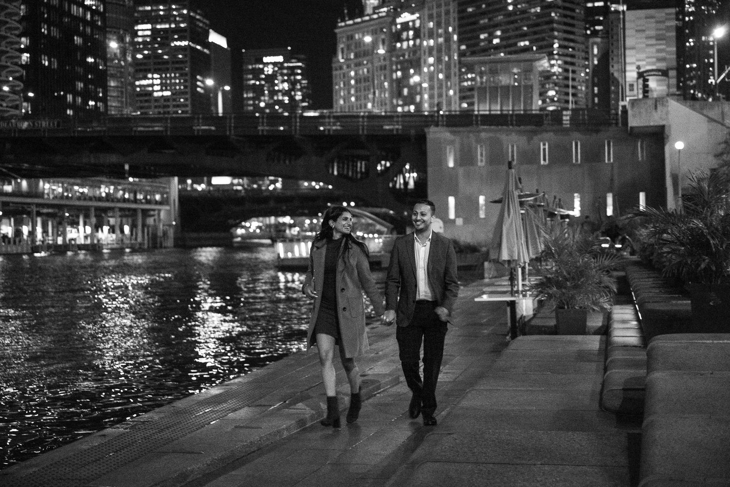 Couple walking along Chicago Riverwalk at night in black and white.