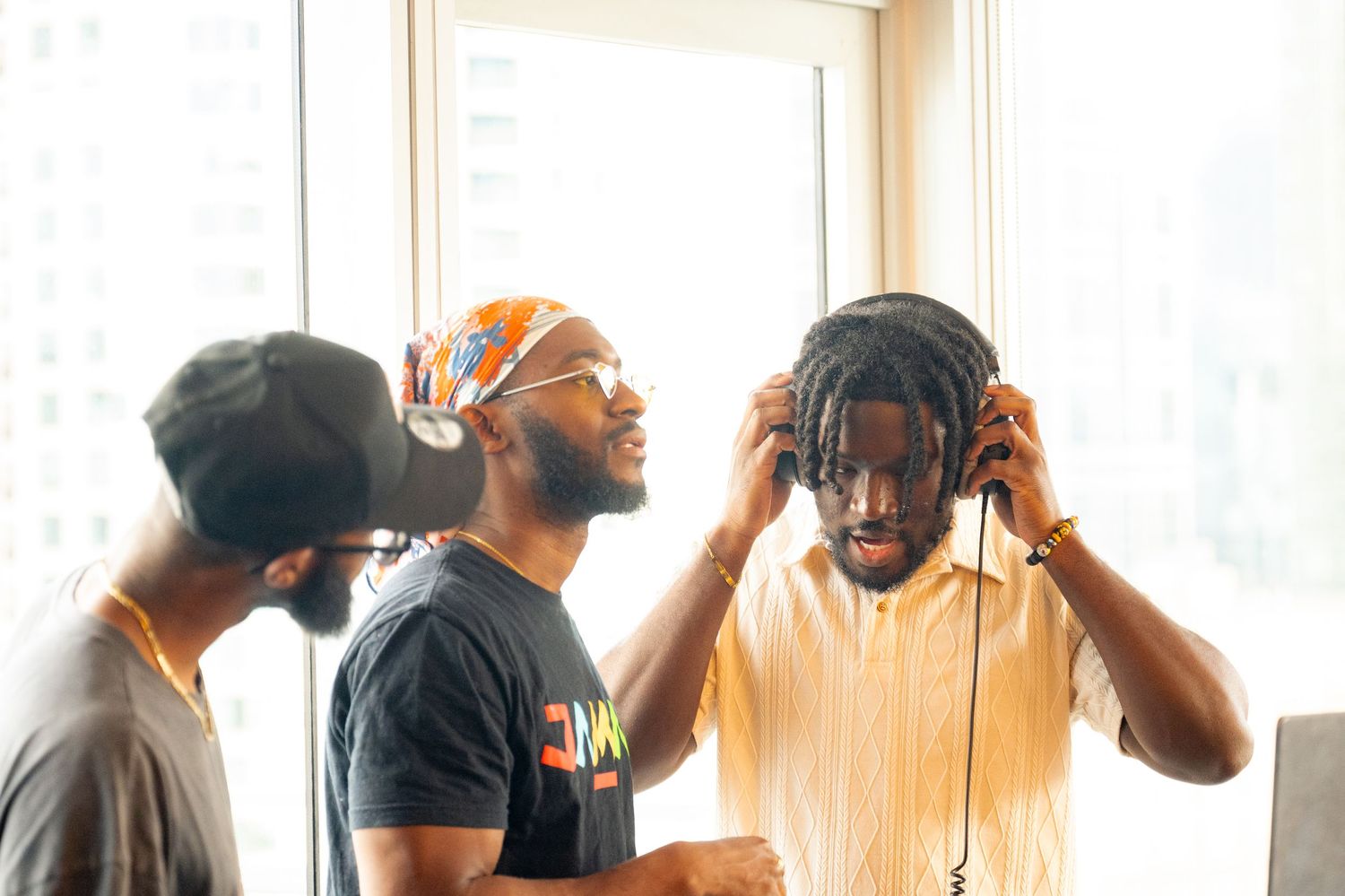 Three people in studio with headphones collaborating on audio project.