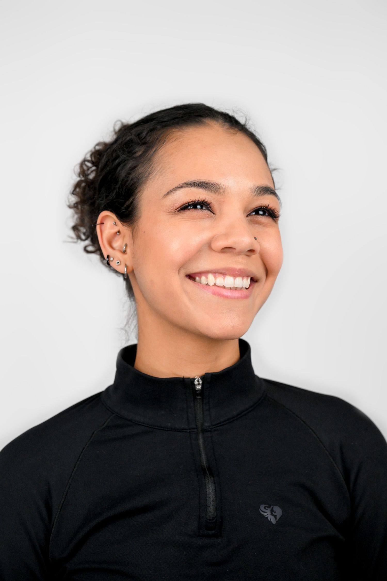 Side profile portrait showing bright smile in black athletic quarter-zip top.