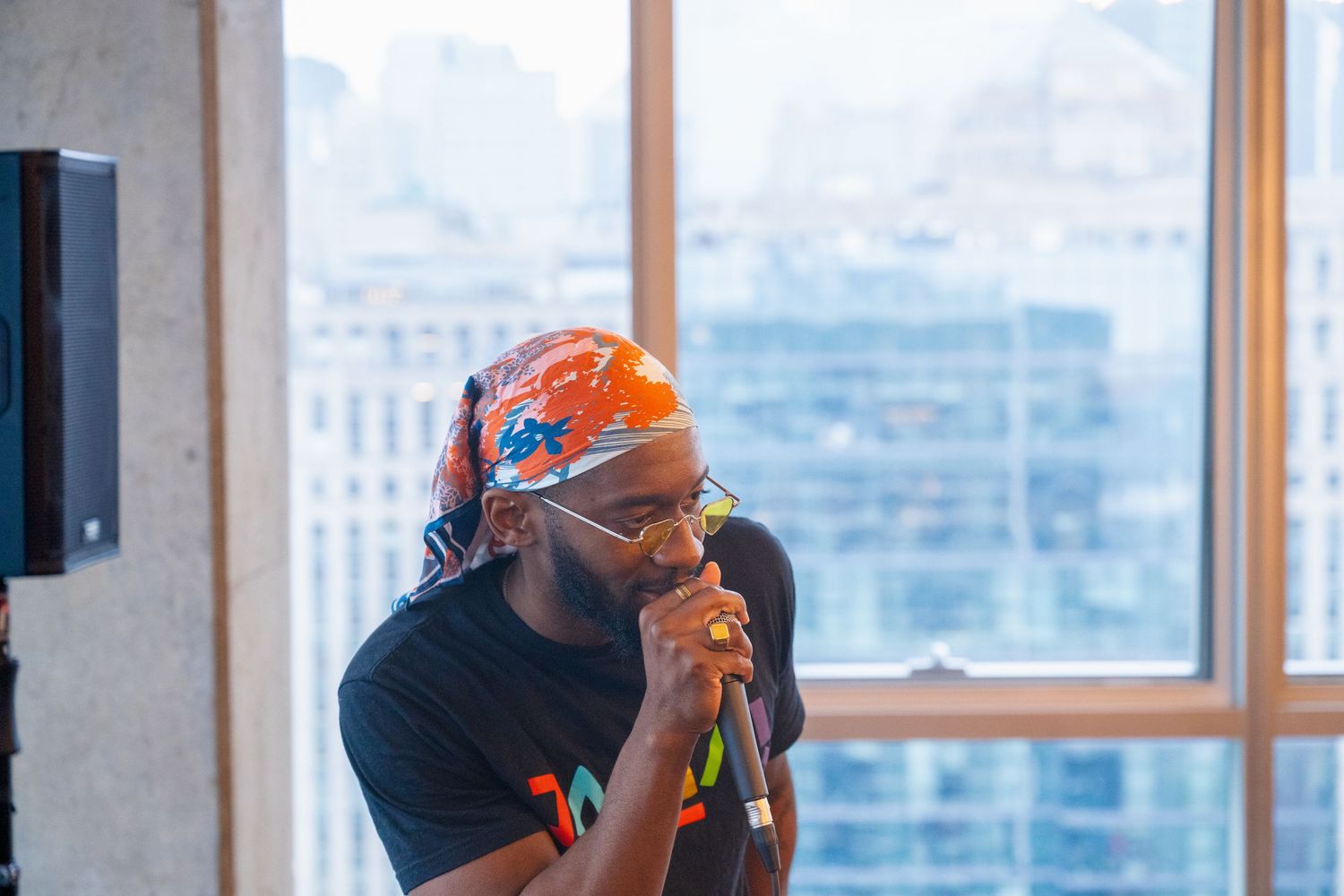Person speaking into microphone wearing orange headband at indoor event.