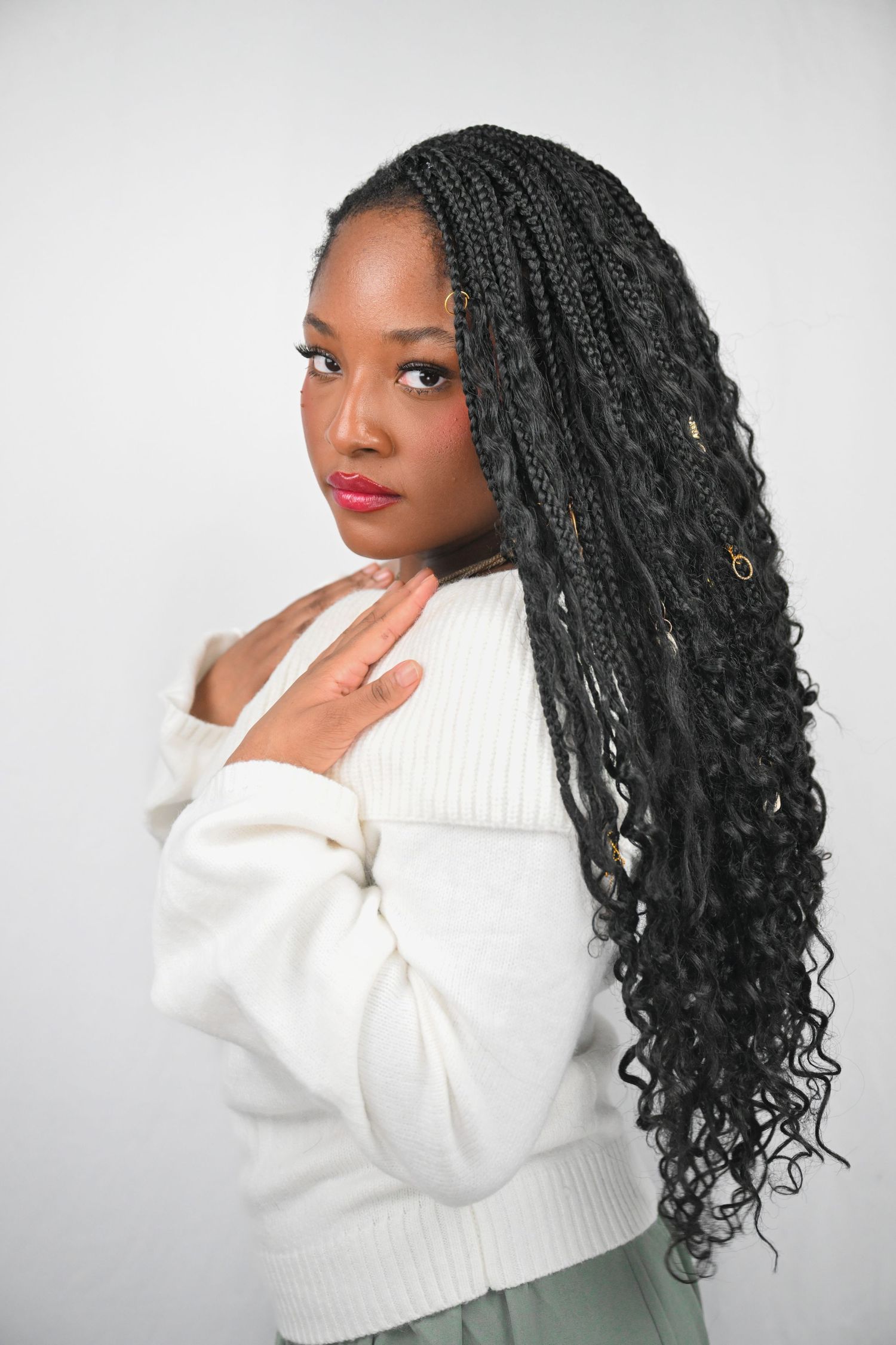 Side profile portraits of someone in a white sweater with long dark braids against a light background.