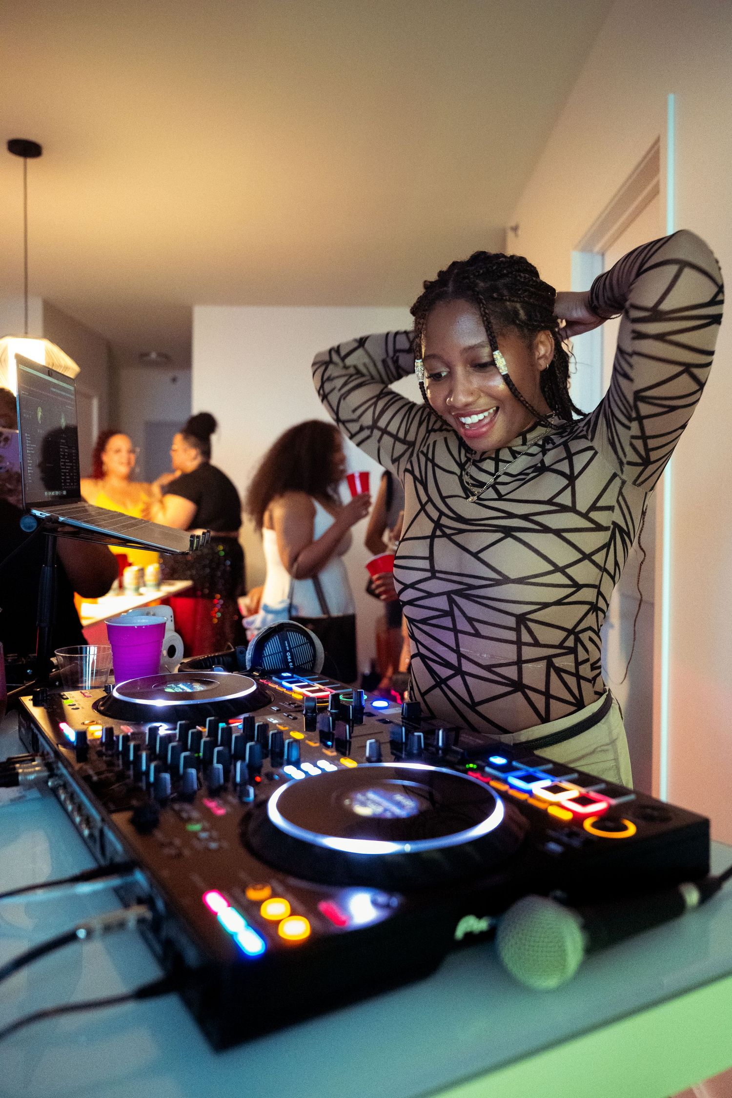 DJ performing with enthusiasm at turntables during party with colorful lights.