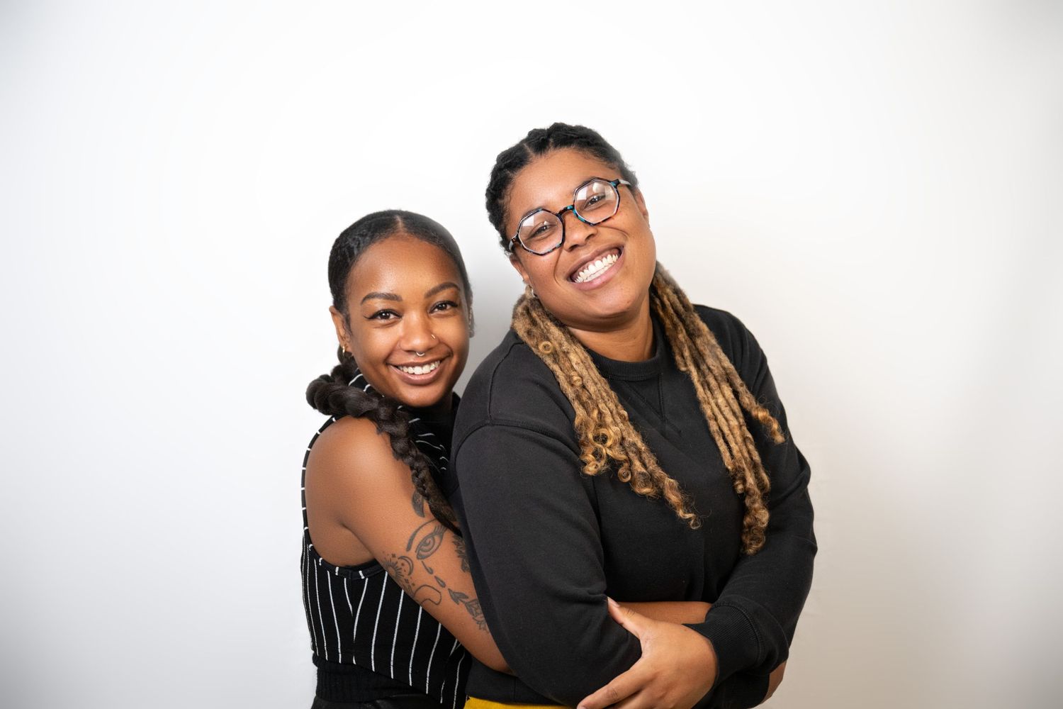 Two people embracing and laughing against white background.