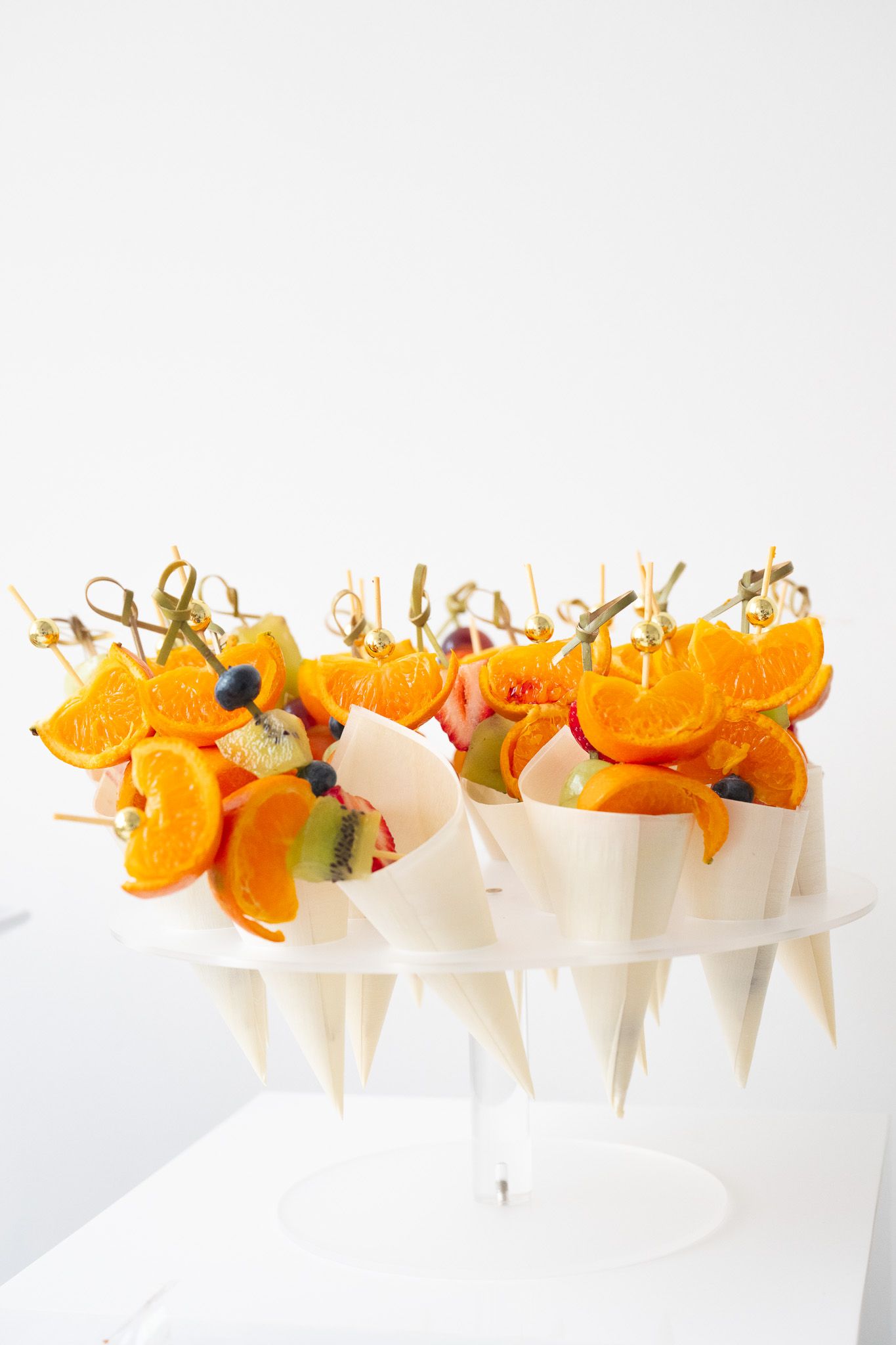 White serving tray holding appetizer skewers garnished with orange slices.