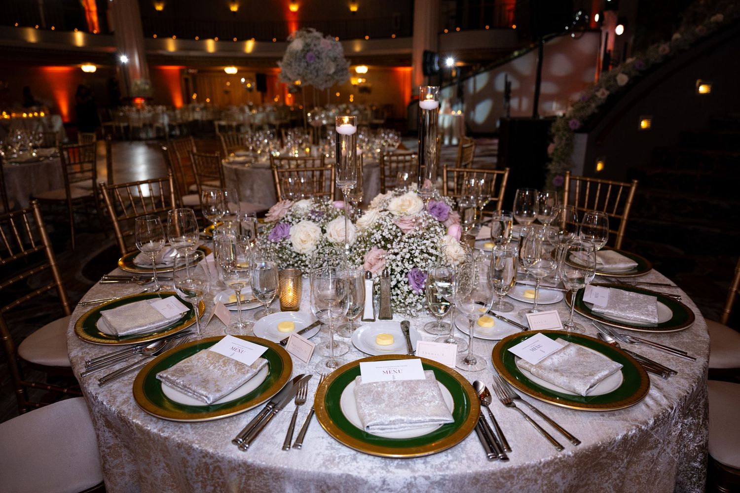 Elegant wedding reception table settings with gold-rimmed plates, crystal glassware, and soft candlelight create a romantic ambiance.