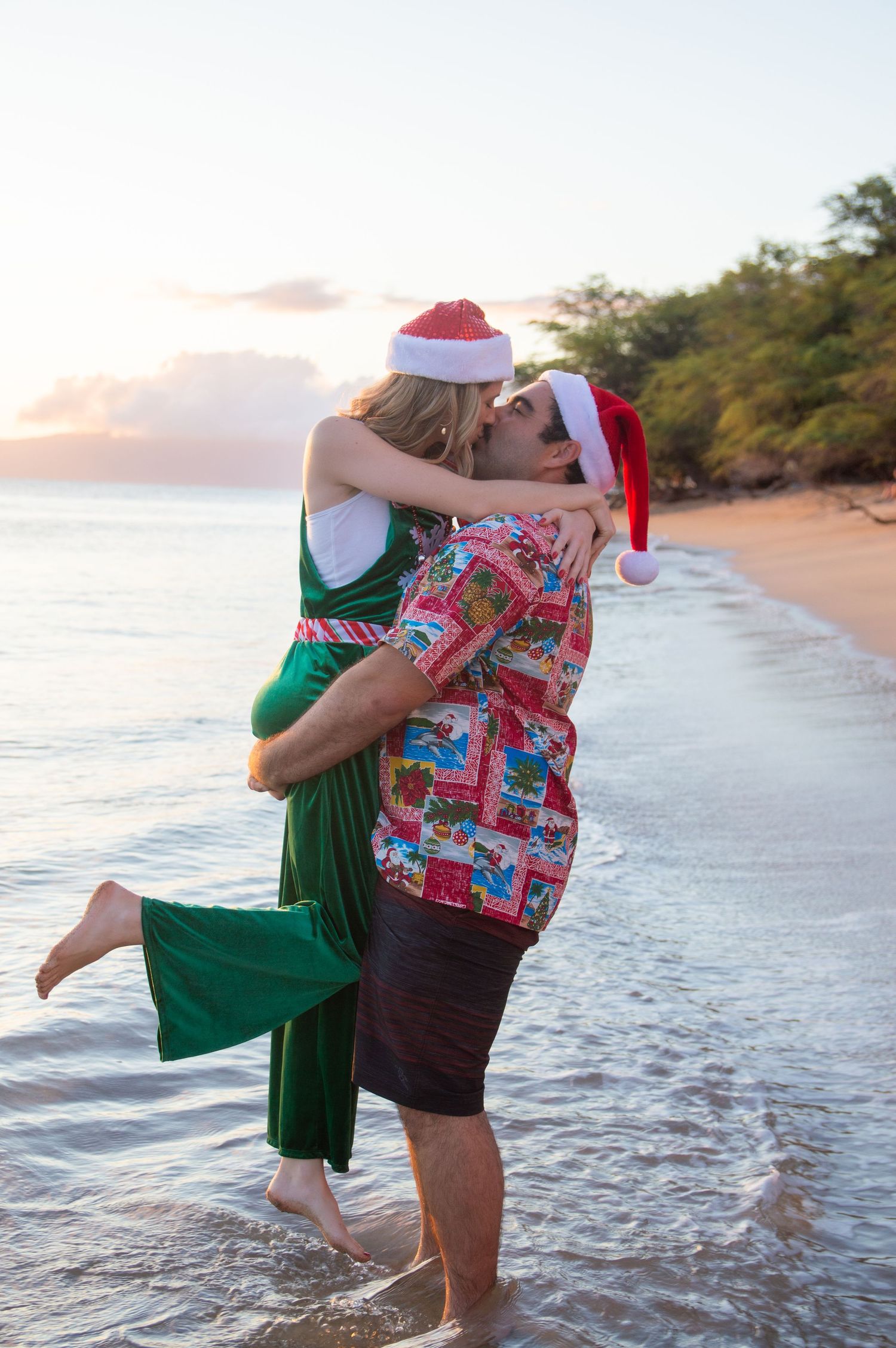 Holiday-themed couple embracing in water at beach during sunset.