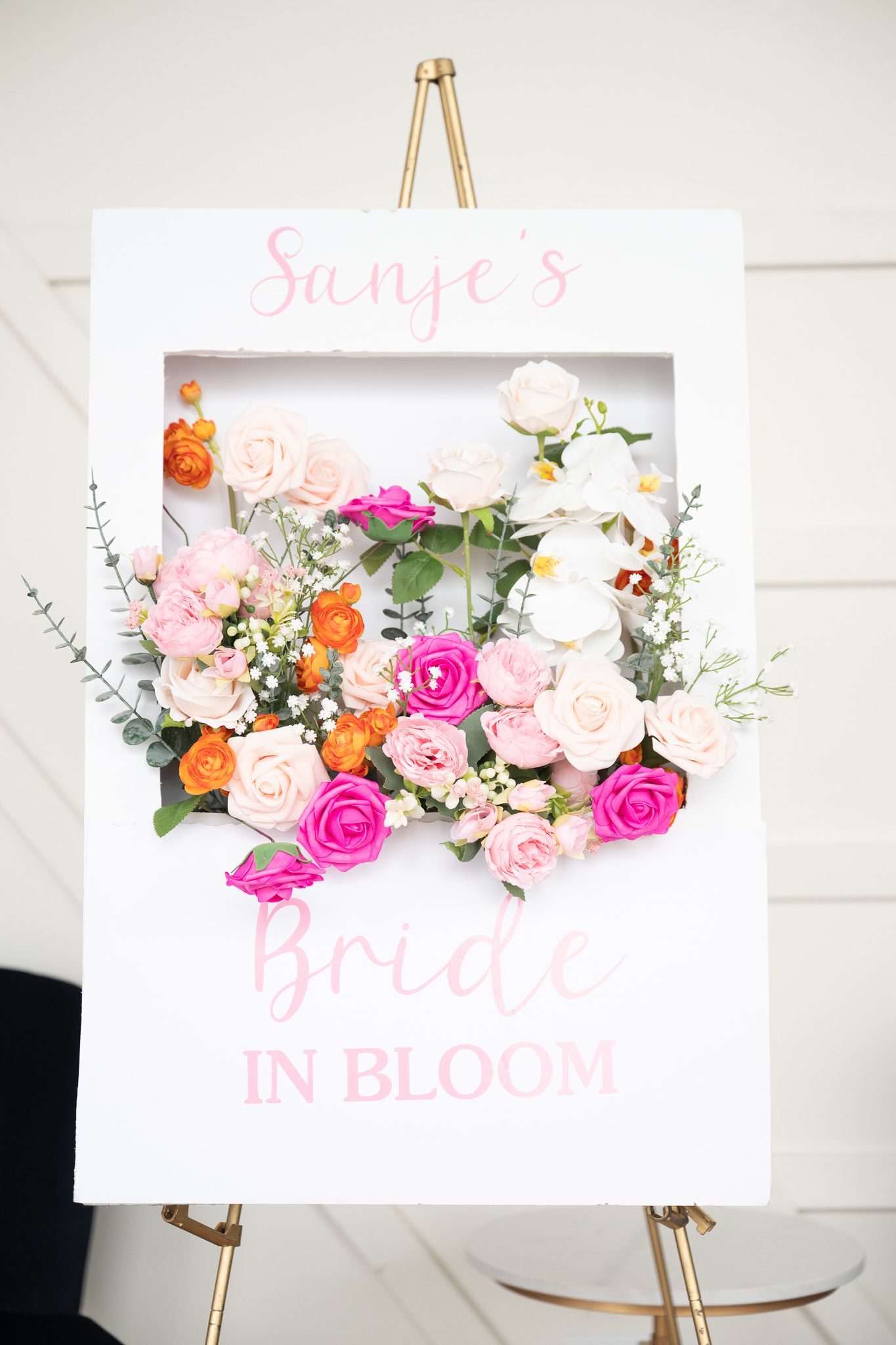 Pink and orange floral arrangement in a white frame reading 'Bride in Bloom'.