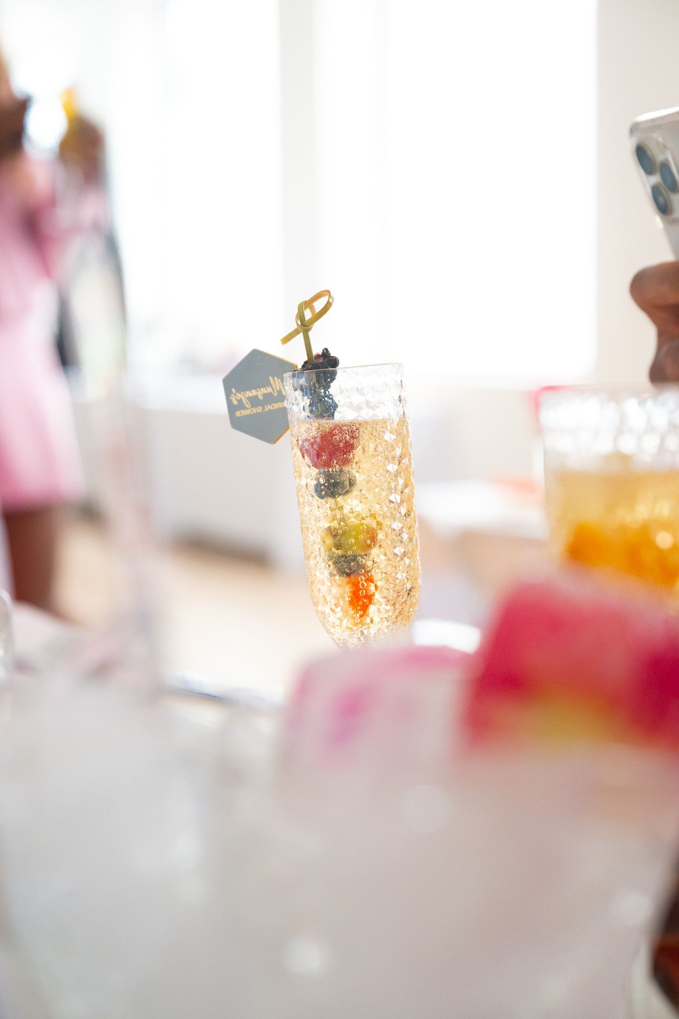 Elegant champagne flute garnished with colorful fruit and a decorative tag.